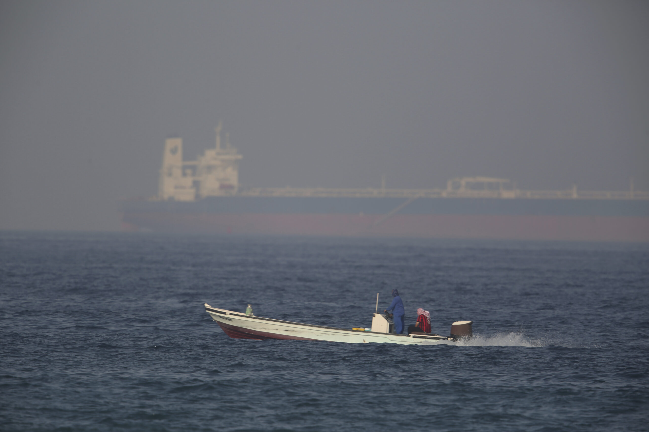 A fishing boat speeds past an oil tanker in the distance in Fujairah, United Arab Emirates, June 15. (AP Photo/Jon Gambrell)