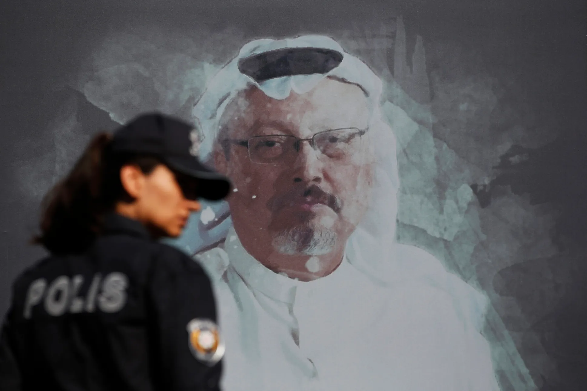 A Turkish police officer walks past a picture of Saudi journalist Jamal Khashoggi prior to a ceremony marking the one-year anniversary of his death, Oct. 2, 2019, Istanbul, Turkey. (AP Photo/Lefteris Pitarakis)
