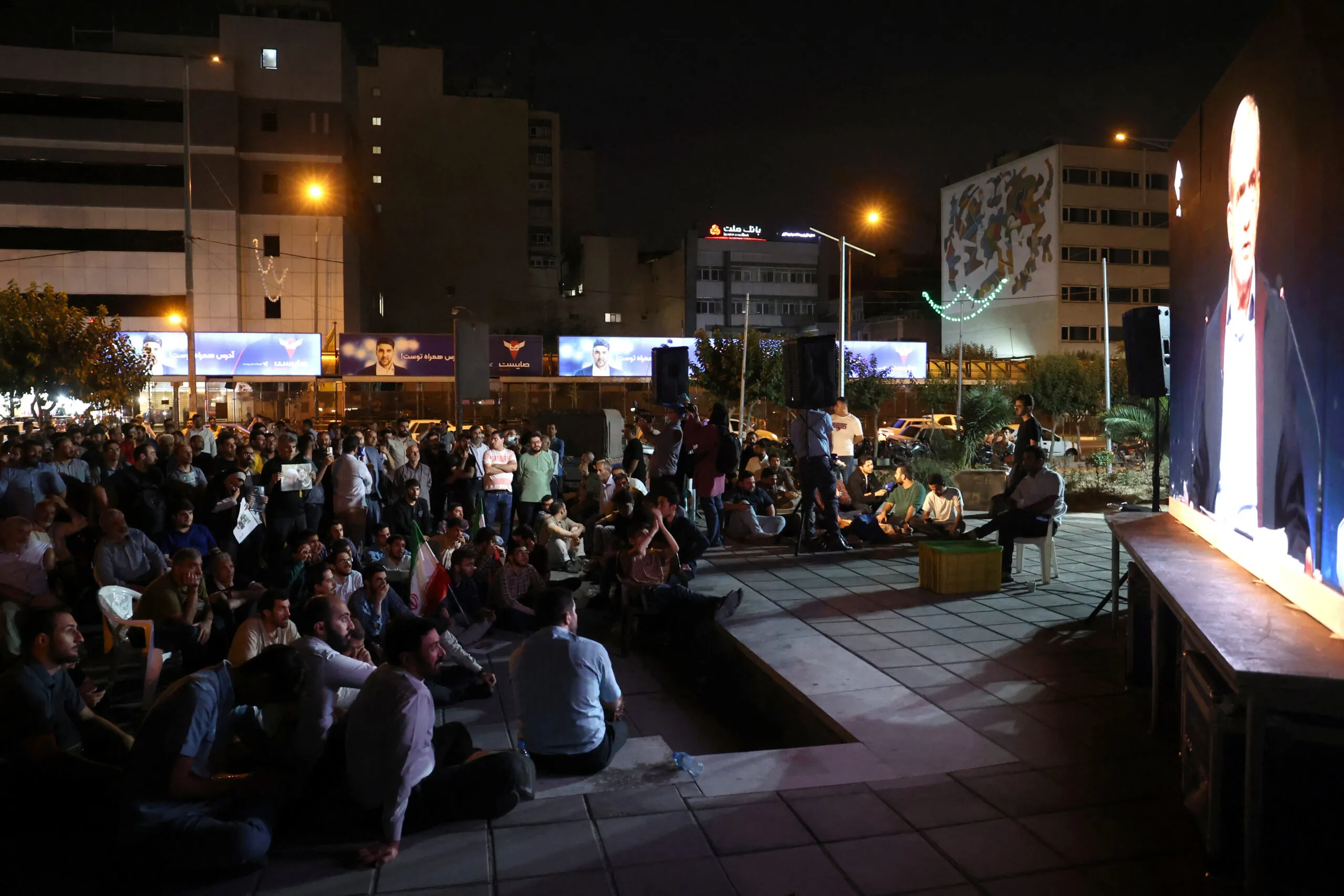 People watch the debate of presidential candidates at a park in Tehran, Iran July 1, 2024. (Majid Asgaripour/ West Asia News Agency via REUTERS)