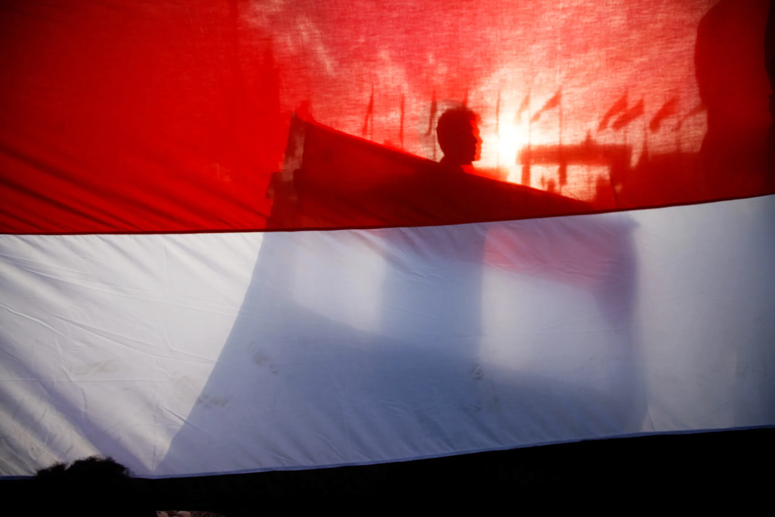 A boy holds a Yemen flag as he stands behind a big flag during a ceremony marking the anniversary of the September 1962 revolution in Sanaa, Yemen, September 26, 2016. (REUTERS/Mohamed al-Sayaghi)
