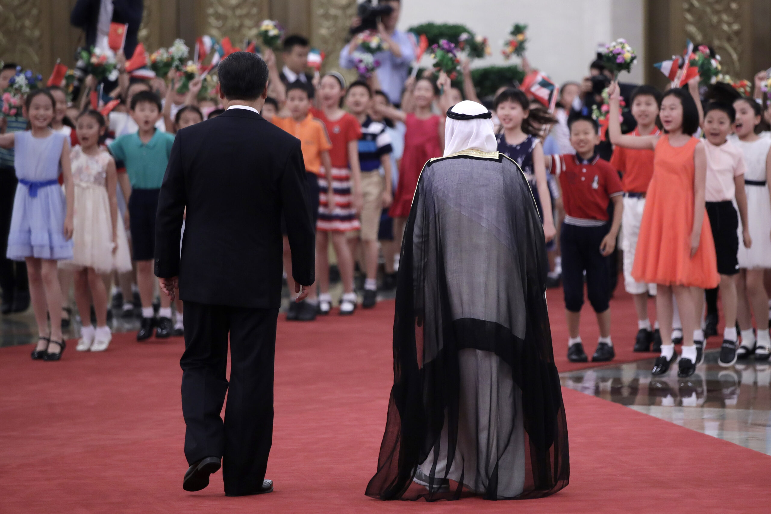 Children wave flags and flowers to welcome Sabah al-Ahmed al-Sabah, then Kuwait's emir, right, during a welcome ceremony hosted by Chinese President Xi Jinping, left, in Beijing, China, July 9, 2018. (AP Photo/Andy Wong)