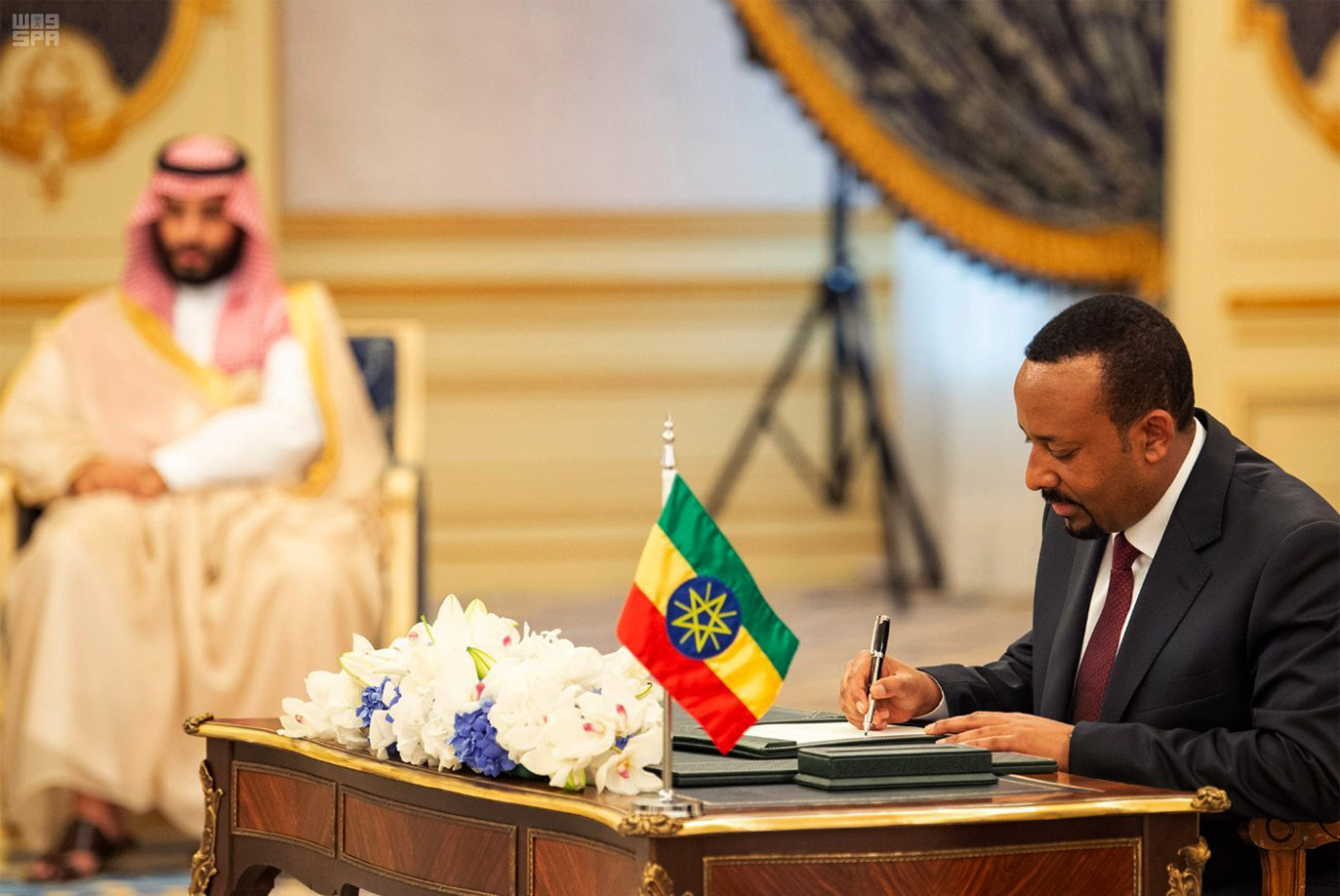 Ethiopian Prime Minister Abiy Ahmed signs a peace accord with Eritrea as Saudi Crown Prince Mohammed bin Salman looks on in the distance in Jiddah, Saudi Arabia, Sept. 16, 2018. (Saudi Press Agency via AP, File)