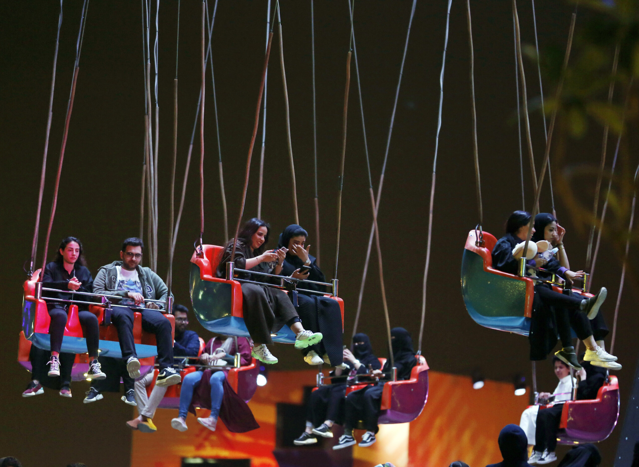 Visitors sit in the swing ride at the Diriyah Oasis amusement park in Diriyah, Saudi Arabia, Dec. 13, 2019. (AP Photo/Amr Nabil)