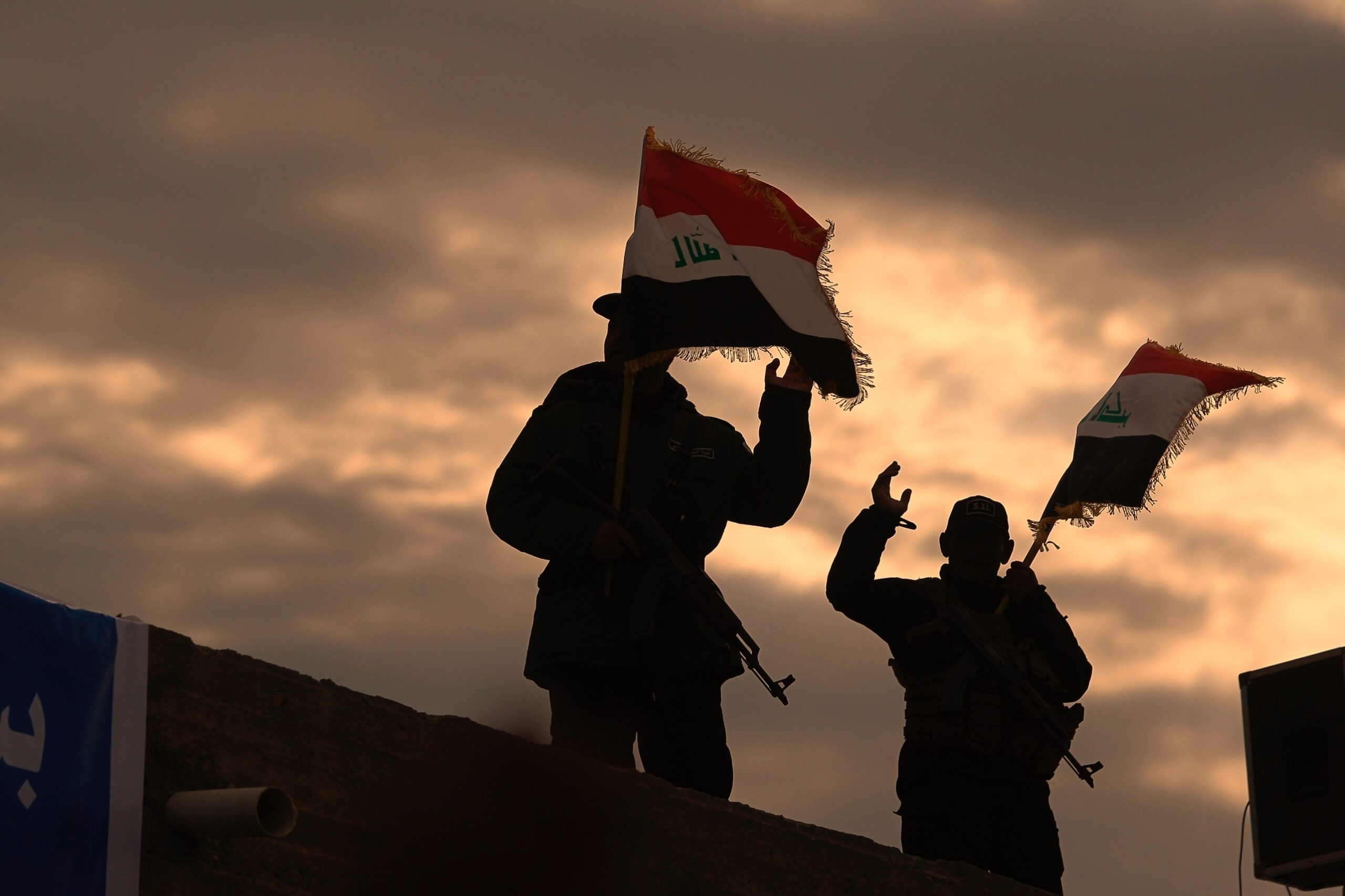 Popular Mobilization Forces wave Iraqi flags while mourners and family members prepare to bury the body of Abu Mahdi al-Muhandis in Najaf, Iraq, Wednesday, Jan. 8. (AP Photo/Anmar Khalil)