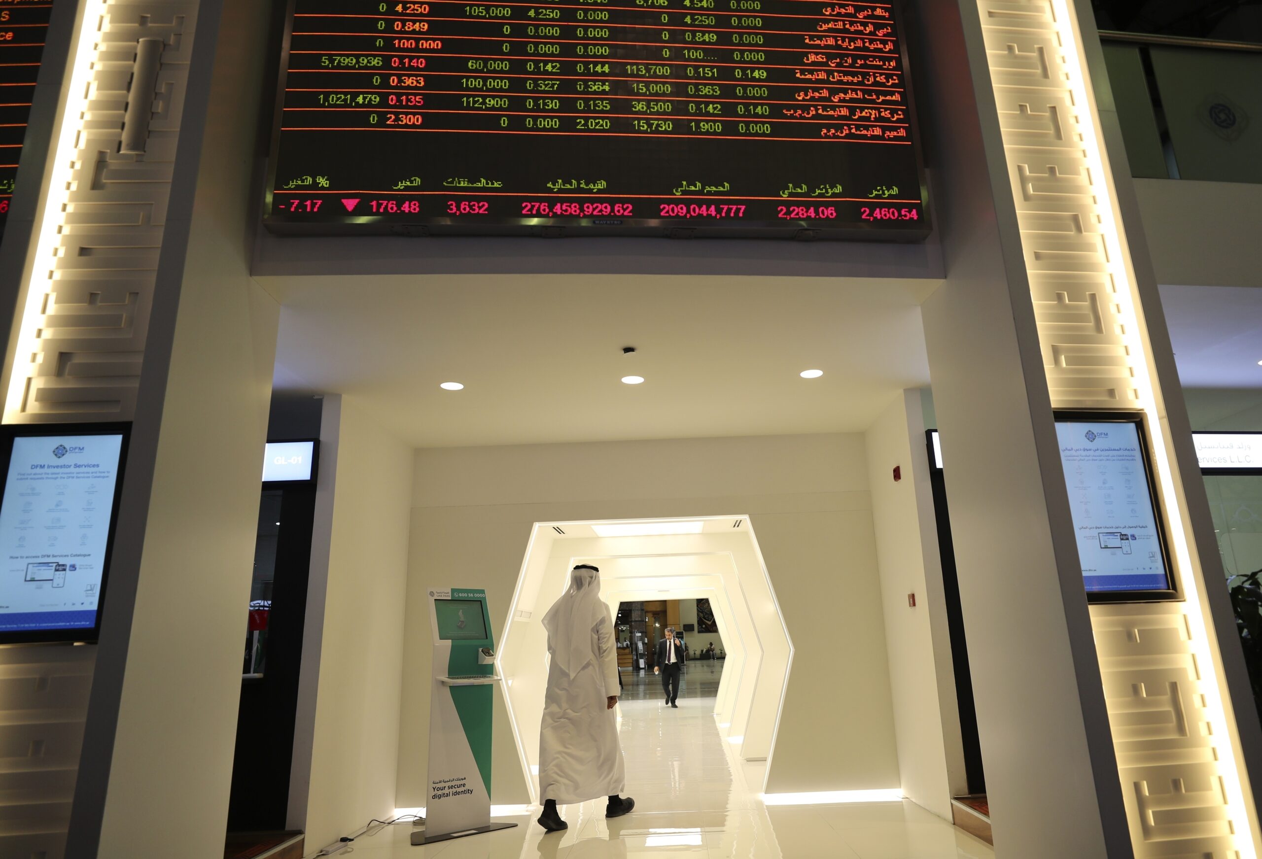 An Emirati trader passes under the stocks display screen at the Dubai Financial Market, March 8, 2020. (AP Photo/Kamran Jebreili)