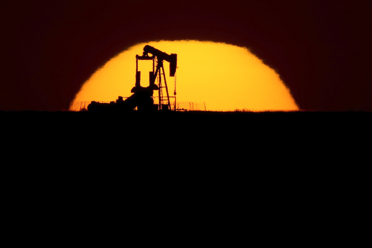 An idle oil pumping unit is silhouetted against the setting sun in a field south of Oakley, Kansas, May 20. (AP Photo/Charlie Riedel)