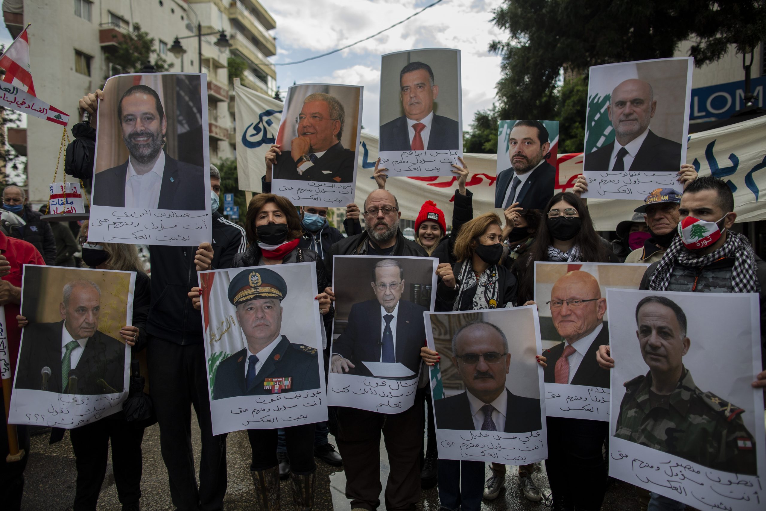 Anti-government protesters hold pictures of Lebanese leaders during a protest, in Beirut's Ashrafieh district, Lebanon, Nov. 26, 2020. (AP Photo/Hassan Ammar)