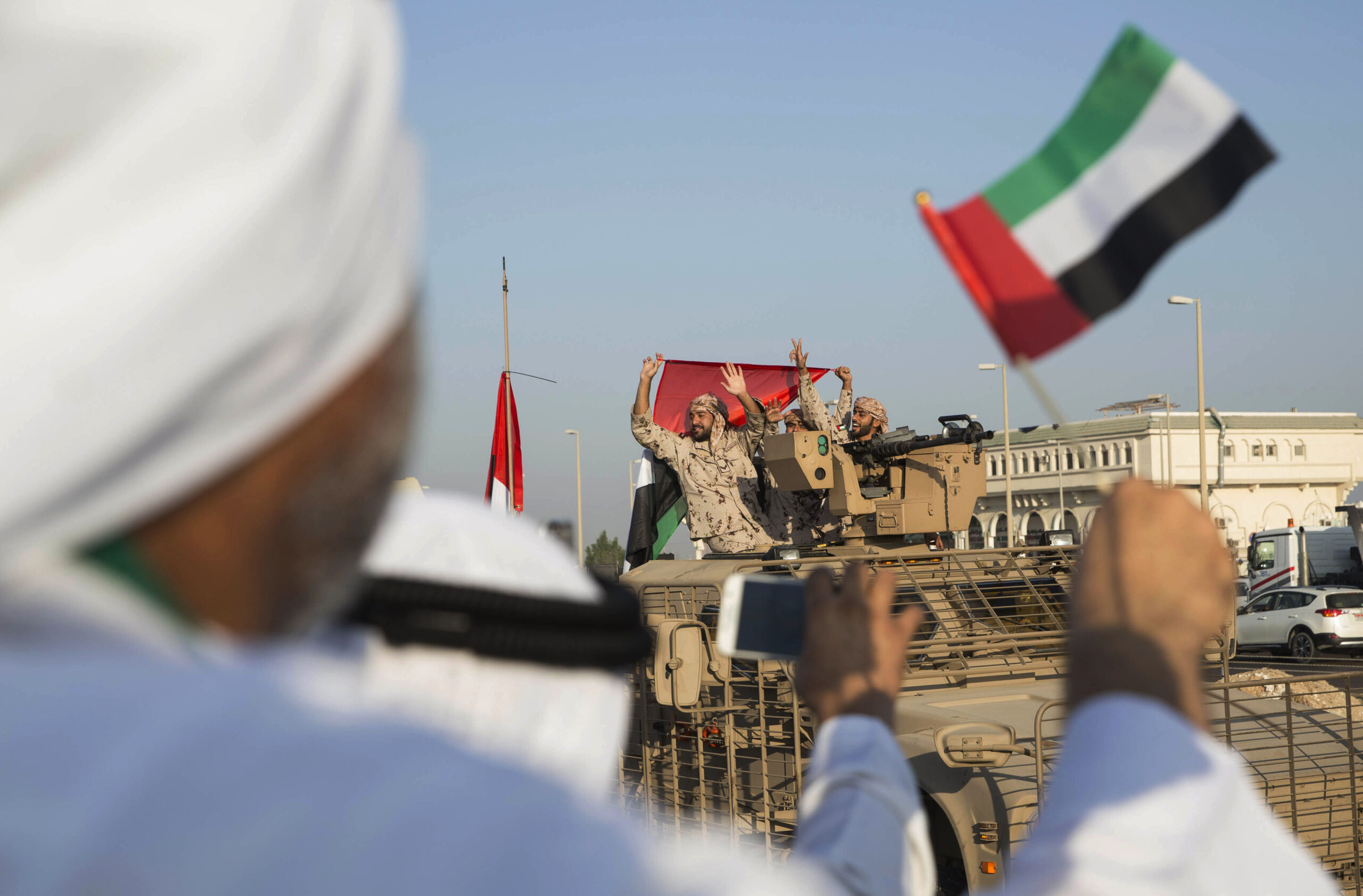 Emiratis wave the UAE flag as a convoy of military vehicles and personnel travels from Al Hamra military base to Zayed Military City in the United Arab Emirates, marking the return of the first group of UAE Armed Forces military personnel from Yemen, Nov. 7, 2015. (Ryan Carter-Crown Prince Court - Abu Dhabi/WAM via AP)