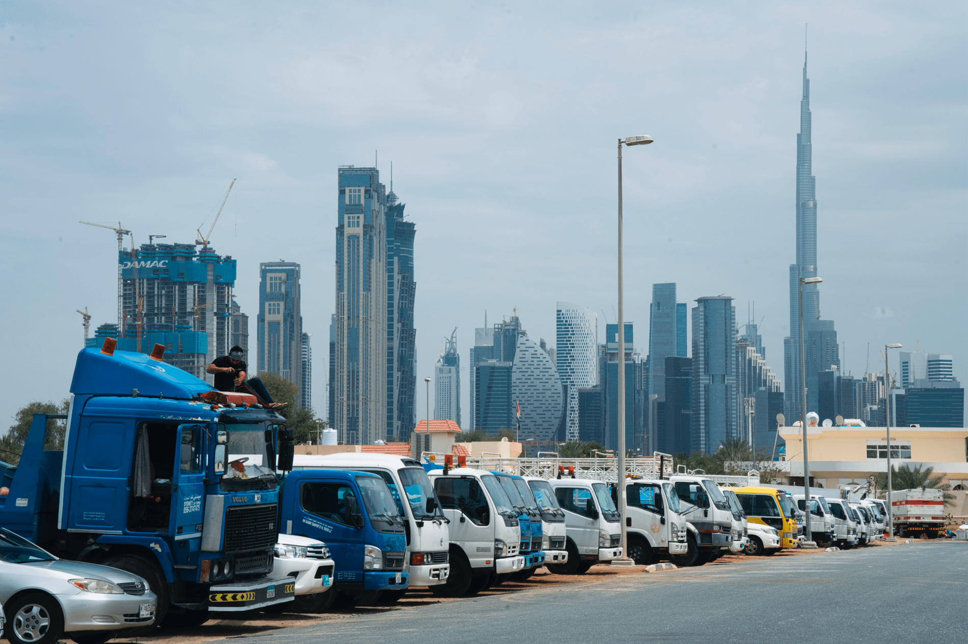 A truck driver works on the cab of his vehicle as Dubai's skyscrapers loom in the background, in Dubai, United Arab Emirates, April 16. (AP Photo/Jon Gambrell)