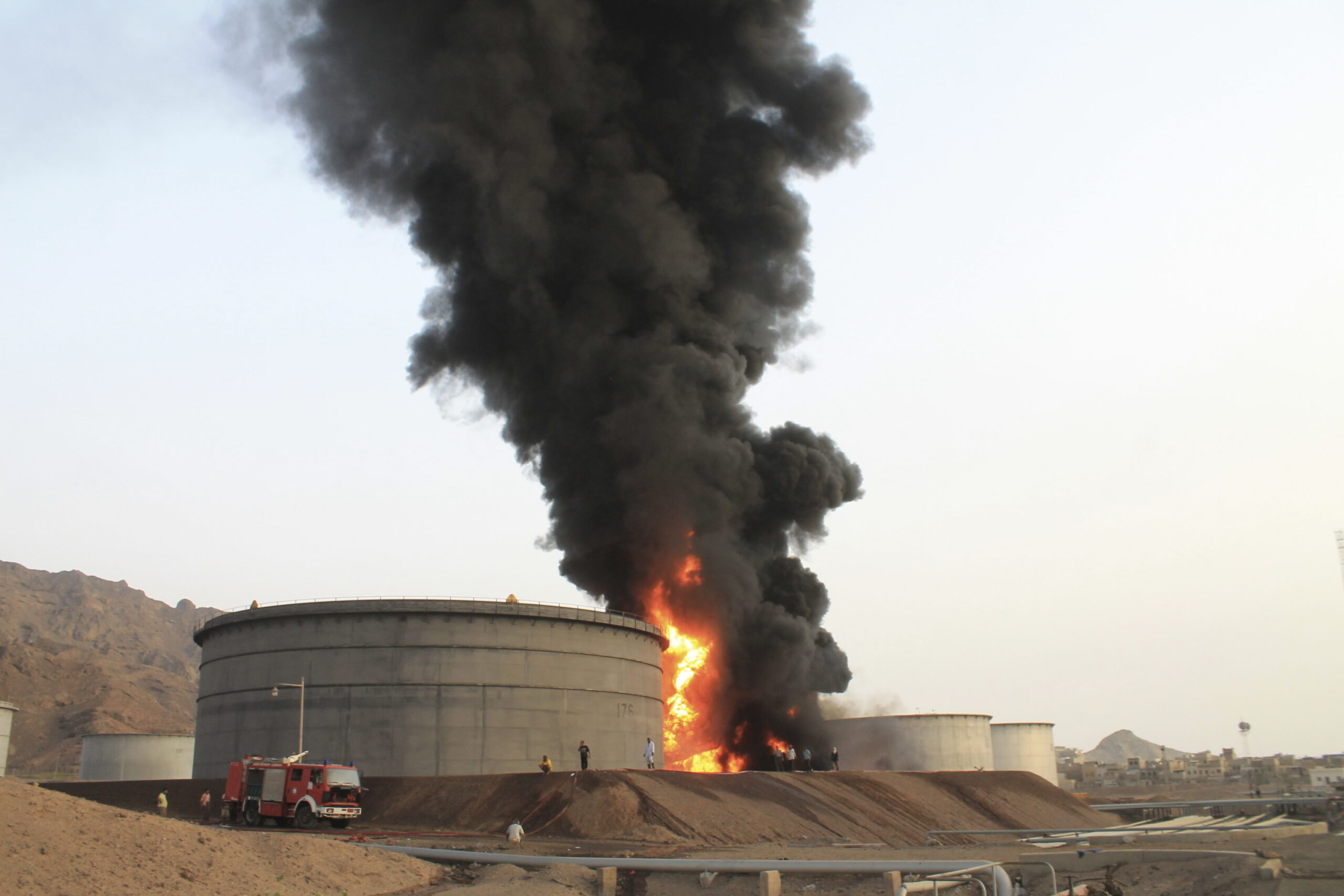 Firefighters work to extinguish a fire following rocket attacks by Houthi fighters at storage tanks of an oil refinery in Aden, Yemen, July 14, 2015. (AP Photo/Abo Muhammed)