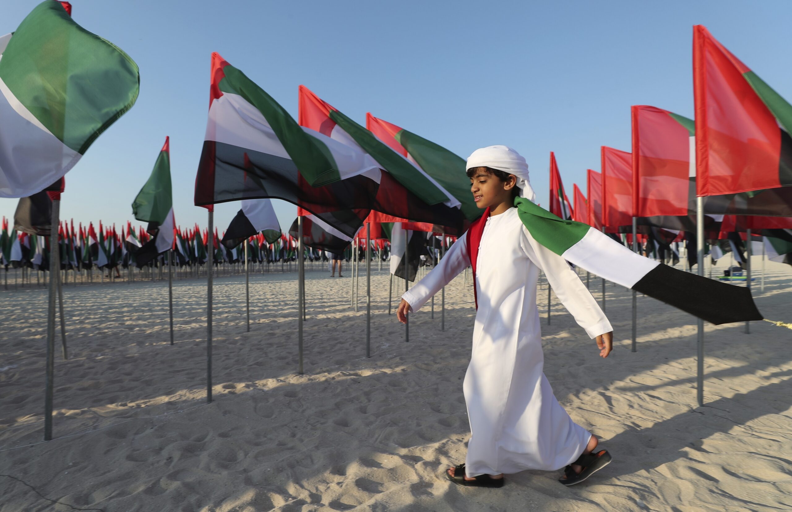 An Emirati boy walks among UAE national flags set up to celebrate the country's Flag Day in Dubai, United Arab Emirates, Nov. 3, 2020. (AP Photo/Kamran Jebreili)