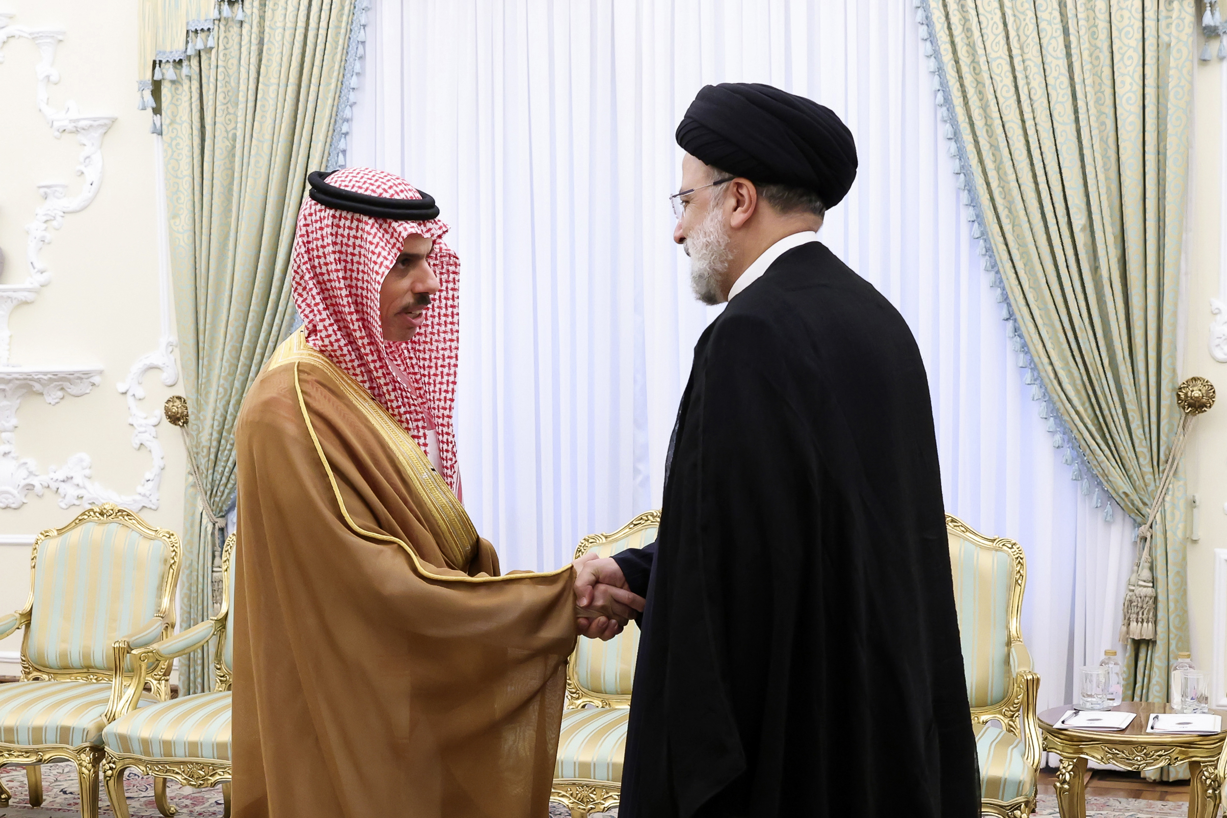 Iranian President Ebrahim Raisi, right, shakes hand with Saudi Foreign Minister Prince Faisal bin Farhan at the Presidency Office in Tehran, Iran, Saturday, June 17. (Iranian Presidency Office via AP)