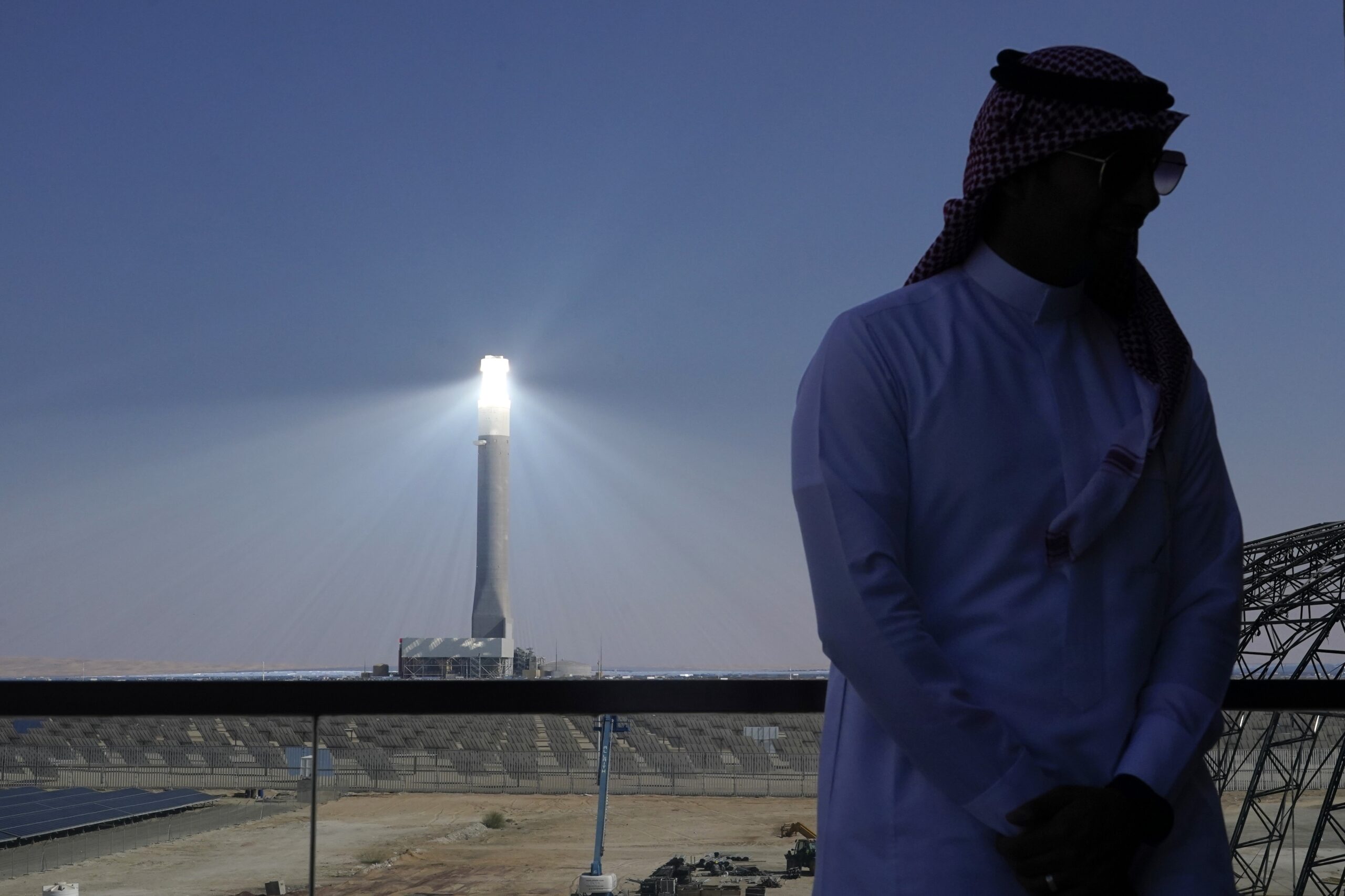 A person stands near a window overlooking solar panels and a solar tower at Mohammed Bin Rashid Al Maktoum Solar Park as Dubai, United Arab Emirates hosts the COP28 U.N. Climate Summit, December 11, 2023. (AP Photo/Joshua A. Bickel)