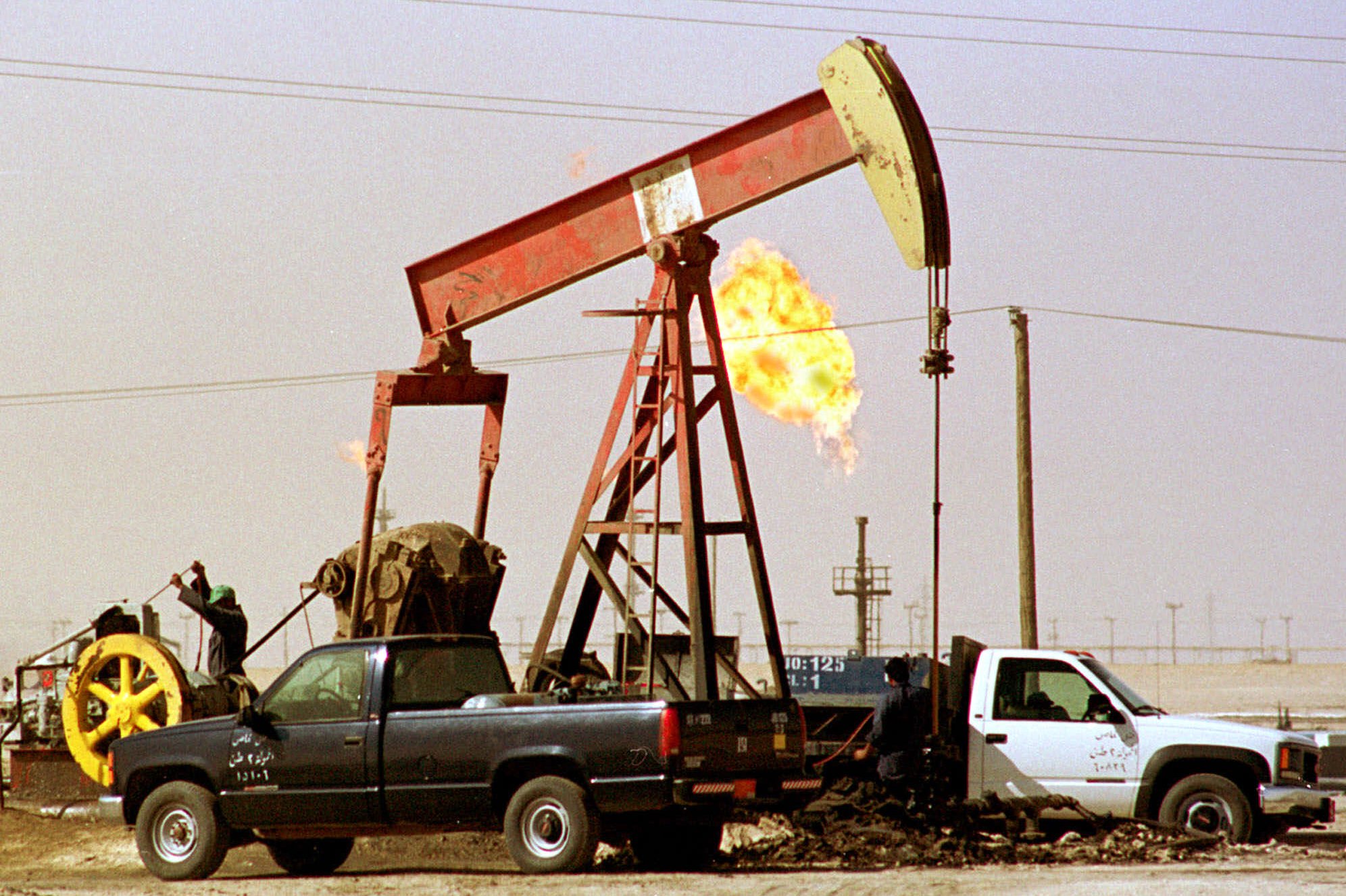 Oil workers doing maintenance tasks on an oil well at Wafra oil field 48 miles south of Kuwait City, Sept. 13, 2000. AP Photo/Gustavo Ferrari)