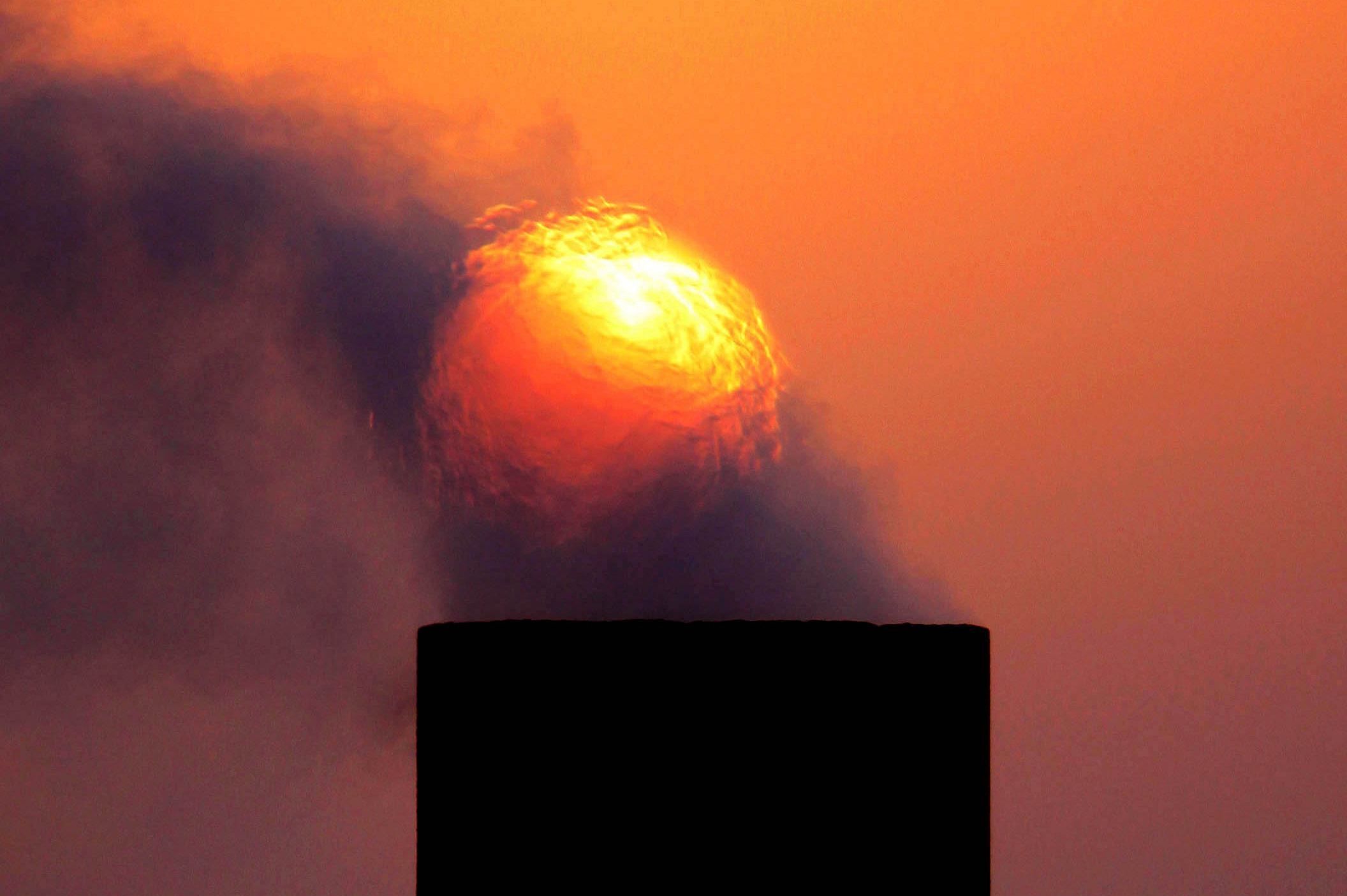 Smoke rises from an oil pipe at sunset in the desert oil field of Sakhir, Bahrain, Sept. 9, 2009. (AP Photo/Hasan Jamali)