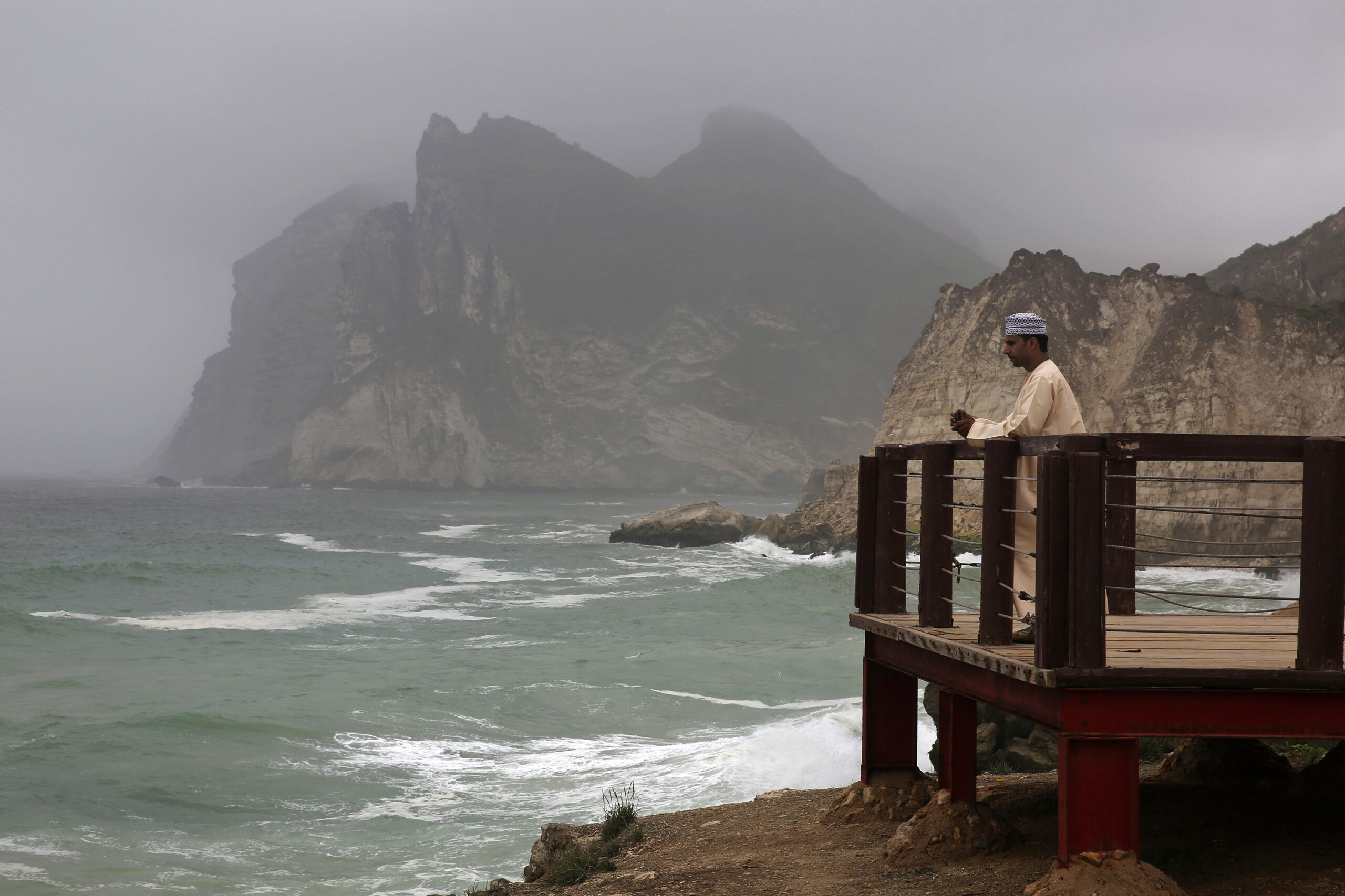A man films waves crashing onto the rocky shore in al-Maghseel, Oman, July 30, 2017. (AP Photo/Sam McNeil)