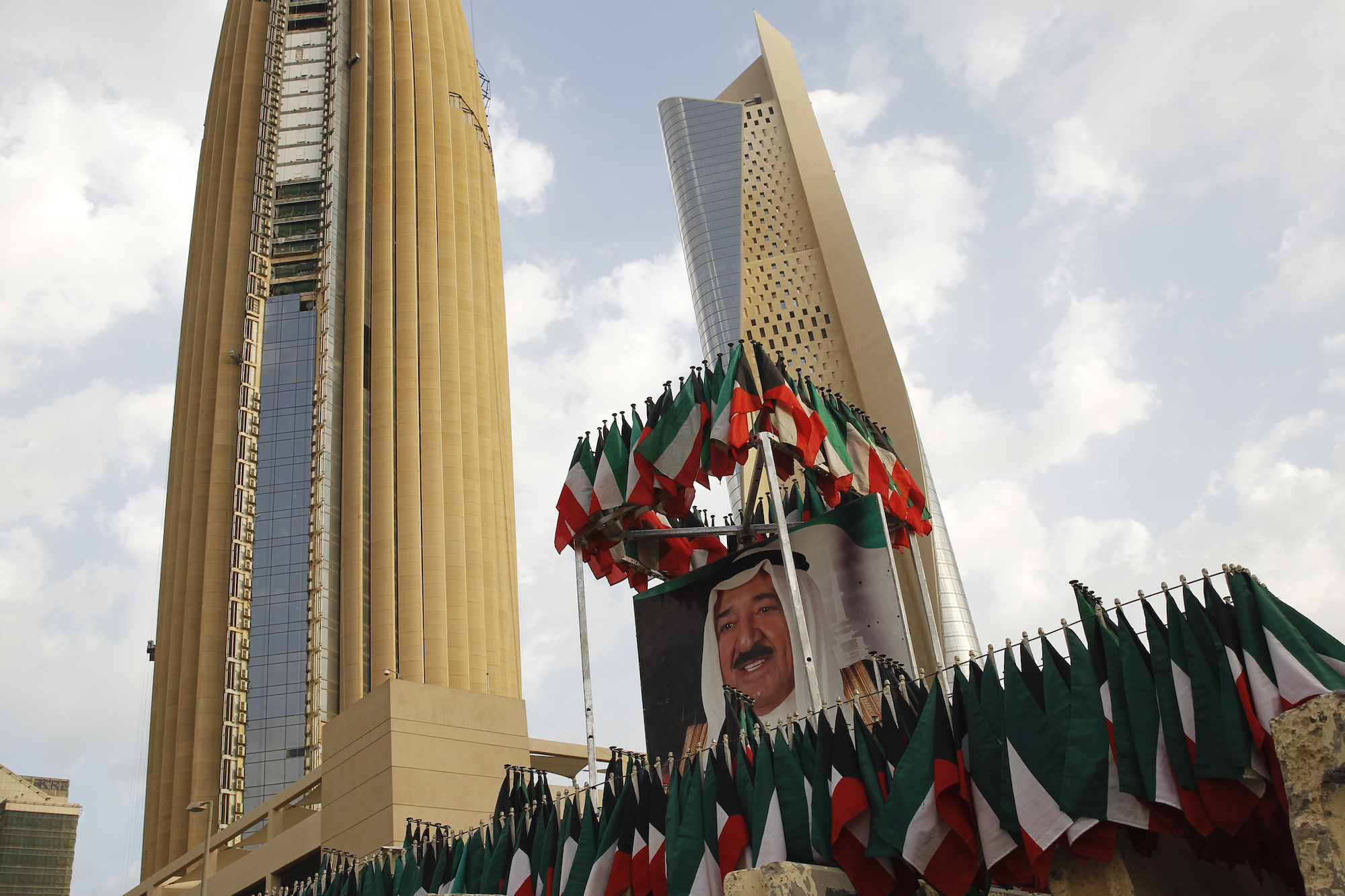 A picture of Kuwait's ruling emir, Emir Sabah al-Ahmed al-Sabah, is displayed with surrounding Kuwaiti flags in Kuwait City, Feb. 14, 2018. (AP Photo/Jon Gambrell)