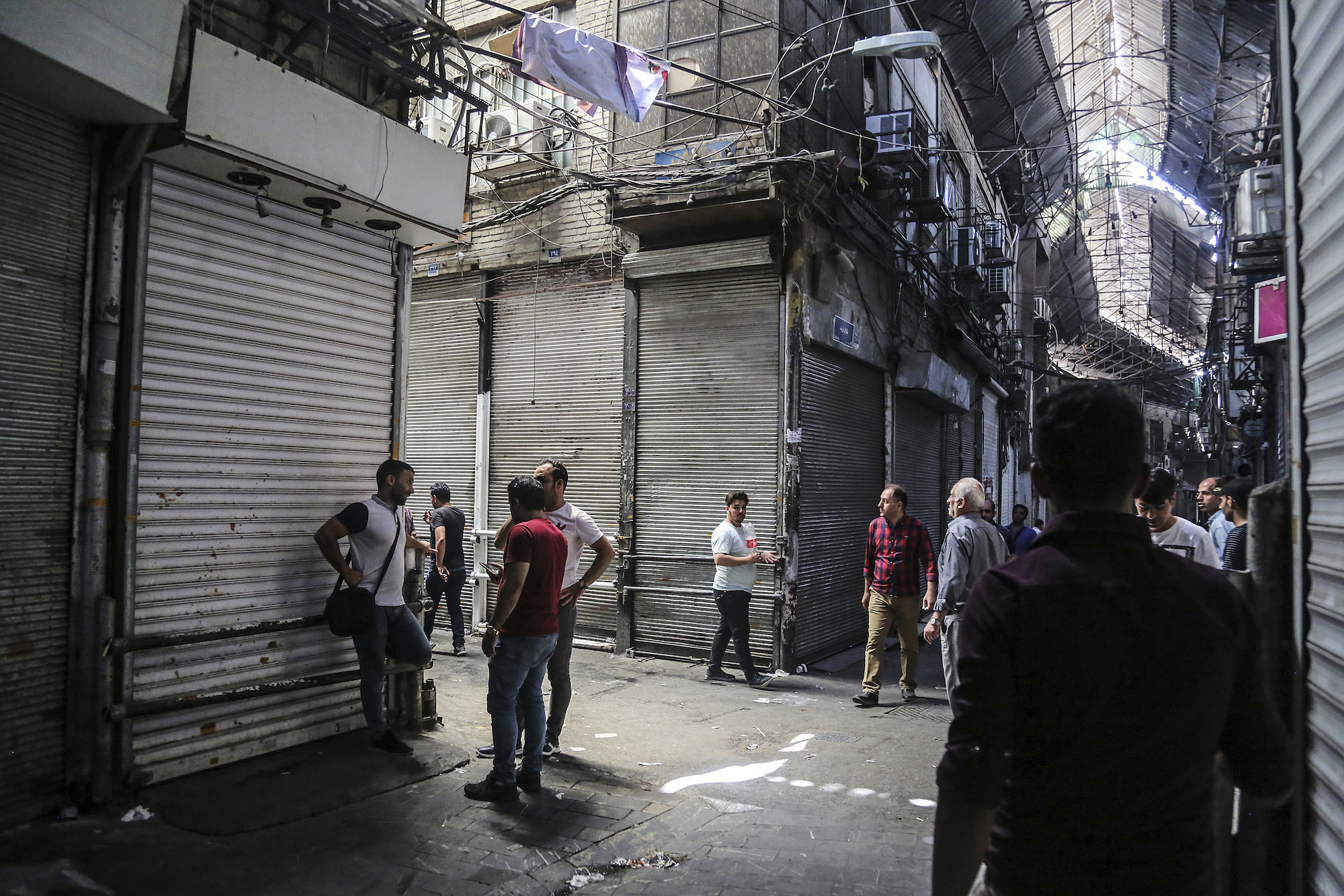 People stand in the old grand bazaar where shops are closed after a protest in Tehran, Iran, June 25. (Iranian Labor News Agency via AP)