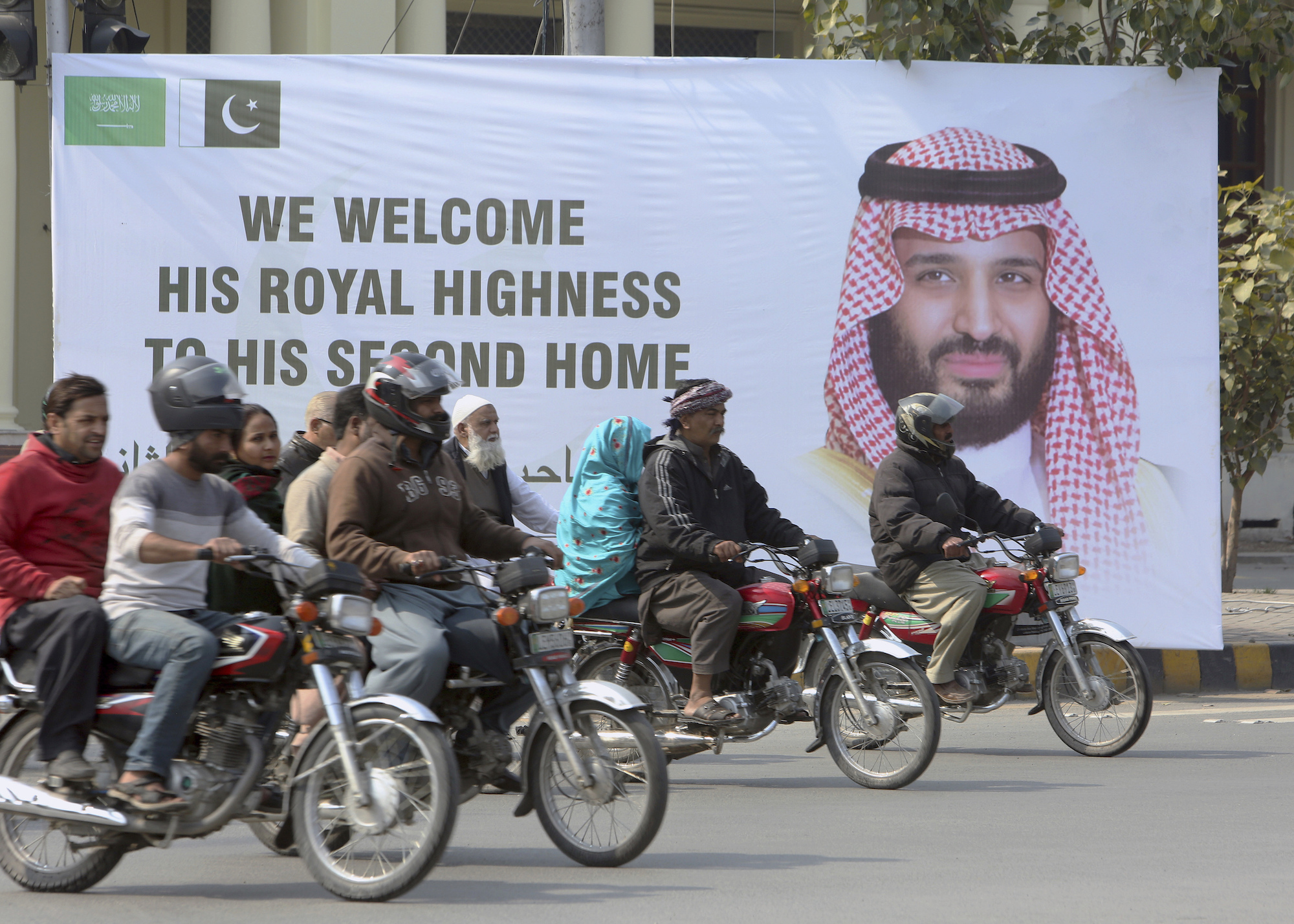 Motorcycle riders drive past a portrait of Saudi Arabia's Crown Prince Mohammed bin Salman displayed on the occasion of his visit to Pakistan, in Lahore, Pakistan, Feb. 16. (AP Photo/K.M. Chaudary)