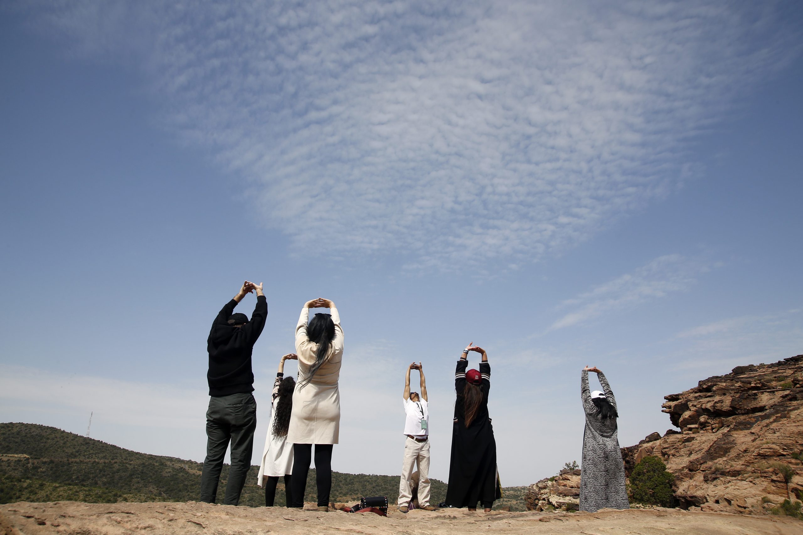 Saudi tourists take part in a guided meditation led by Alwaleed al-Keaid, center, who runs a Saudi hiking company, at the Red Rock mountain during the al-Soudah festival in Abha, Saudi Arabia, Aug. 24, 2019. (AP Photo/Amr Nabil)