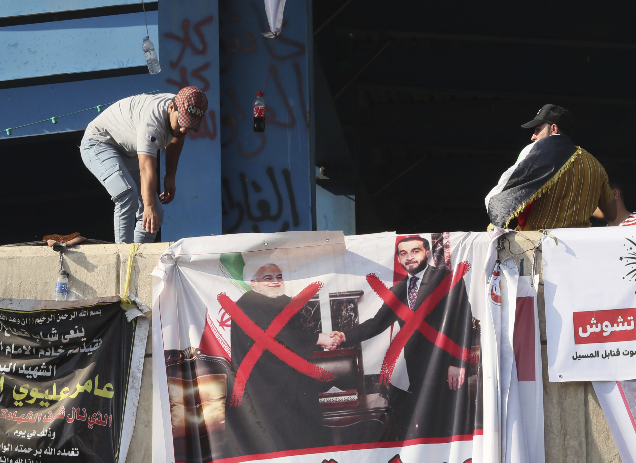 A poster of Iraqi Parliament Speaker Mohammed al-Halbousi, right, and Iranian President Hassan Rouhani, left, hang on a building near Tahrir Square, during ongoing protests in Baghdad, Iraq, Nov. 6. (AP Photo/Hadi Mizban)