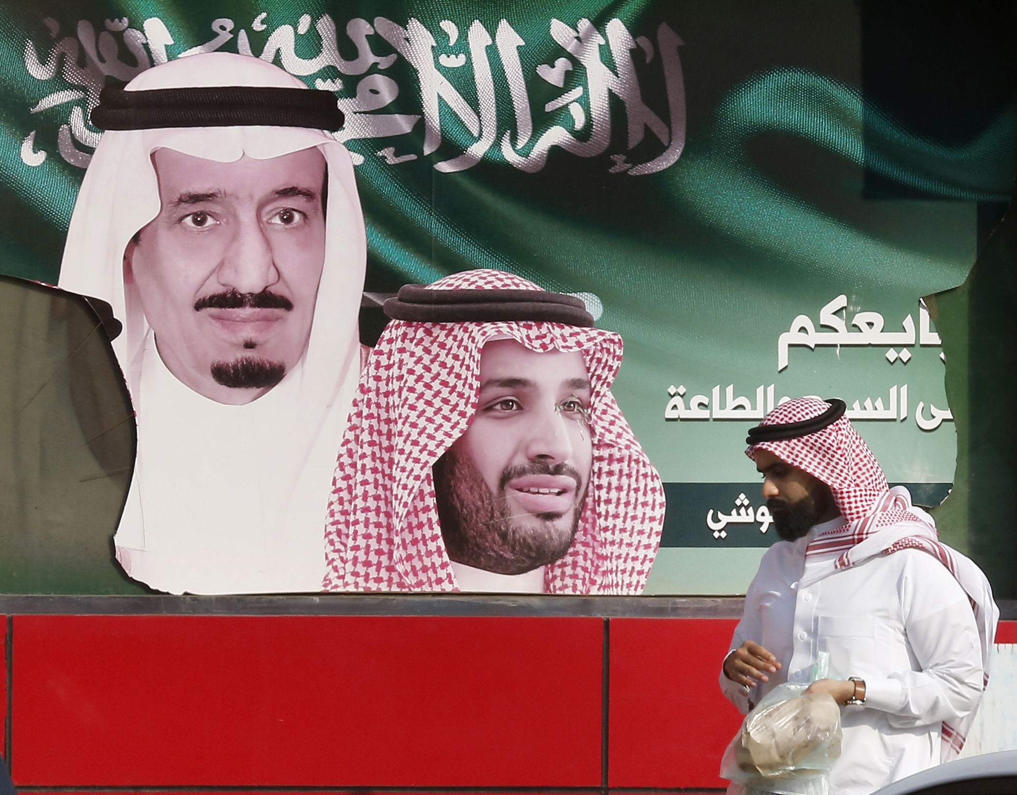 A man walks past a banner showing Saudi King Salman bin Abdulaziz, left, and Crown Prince Mohammed bin Salman, Jeddah, Saudi Arabia, Nov. 12, 2019. (AP Photo/Amr Nabil)