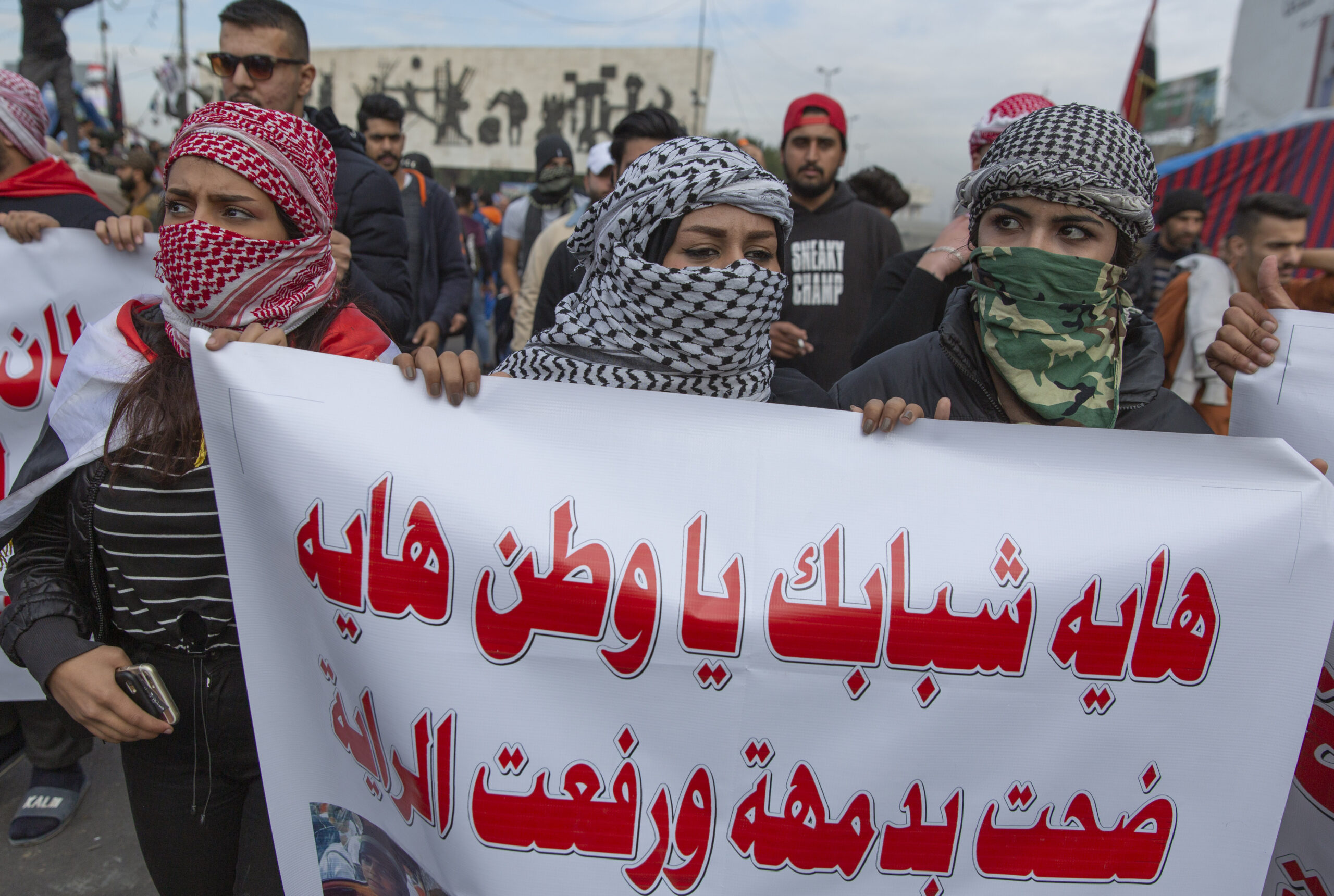 Iraqi protesters carry a poster that reads in Arabic, "Those are your youths, Iraq, they sacrificed their blood and carried the flag," during ongoing protests in Baghdad, Iraq, Jan. 10, 2020. (AP Photo/Nasser Nasser)