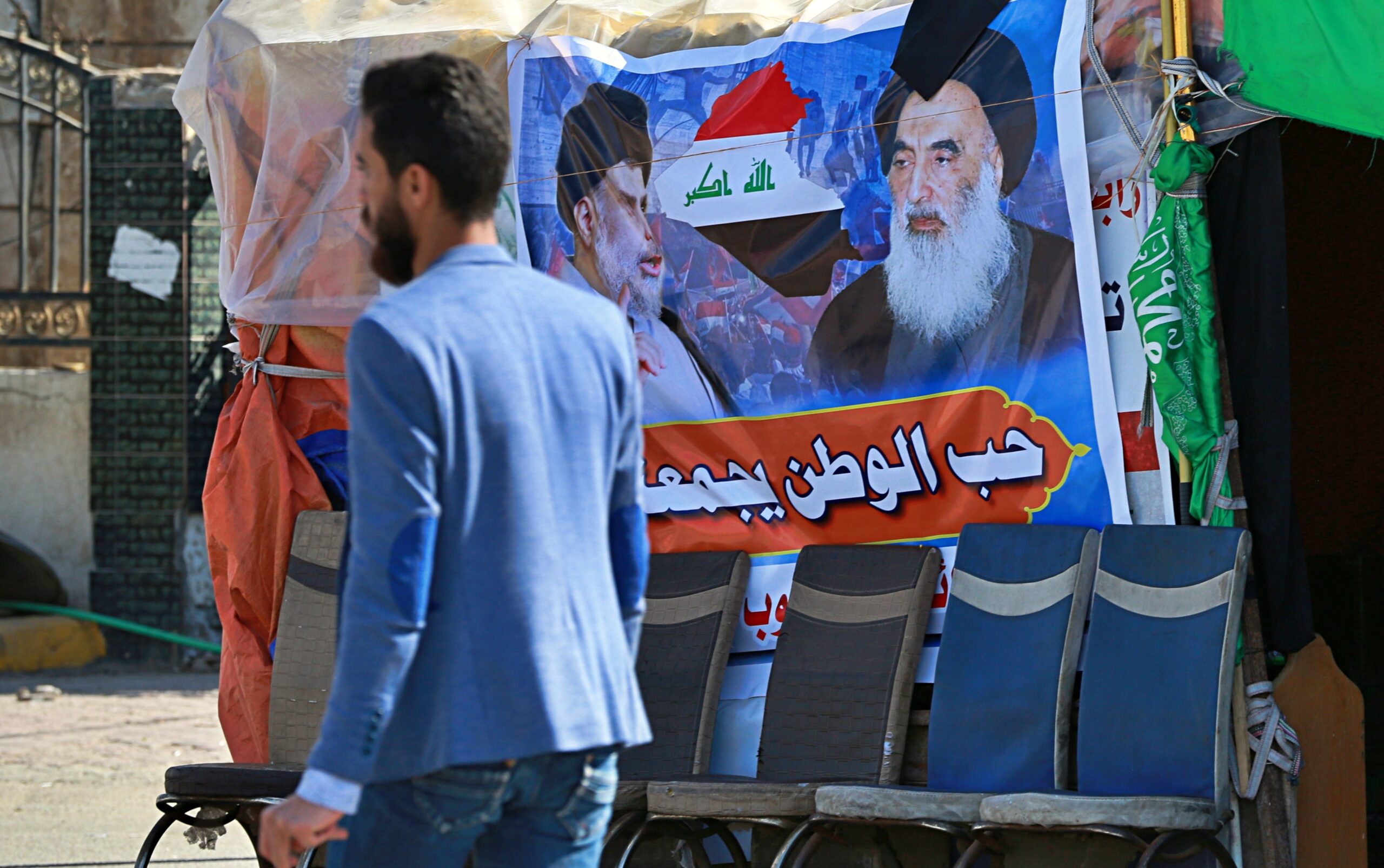 A poster of Shia spiritual leader Grand Ayatollah Ali al-Sistani, right, and Arabic that reads, 'Love of the country bonds us together,' is hung in a site of protests, in Najaf, Iraq, February 2, 2020. (AP Photo/Hadi Mizban)