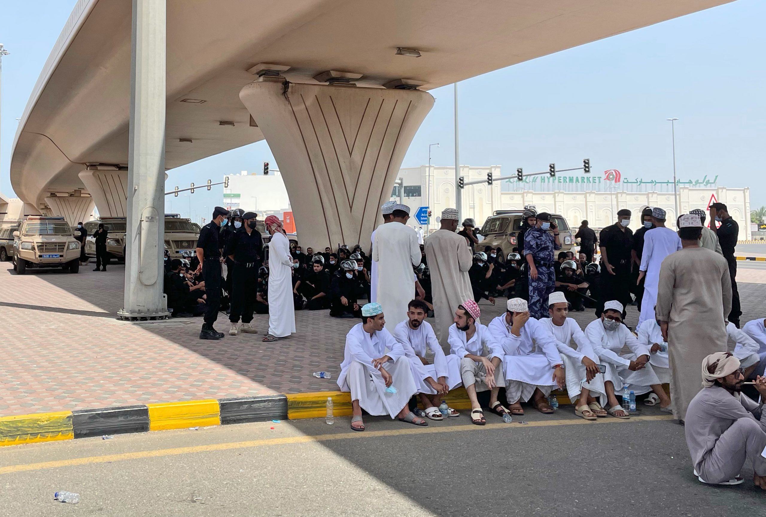 People and police forces talk on the street in Sohar, Oman, May 25. (AP Photo)