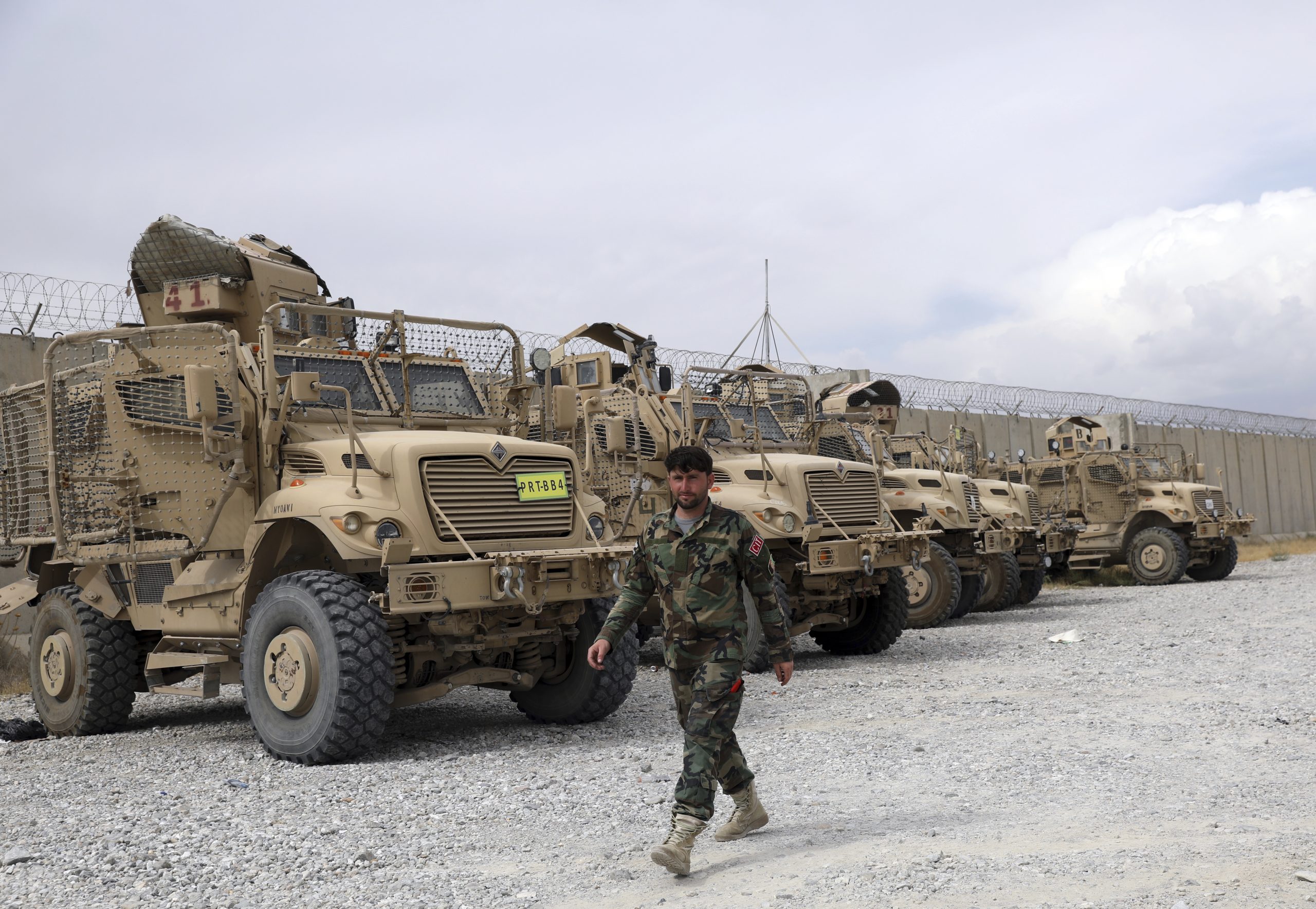 An Afghan army soldier walks past Mine Resistant Ambush Protected vehicles that were left after the U.S. military left Bagram air base, in Parwan province north of Kabul, Afghanistan, July 5. (AP Photo/Rahmat Gul)