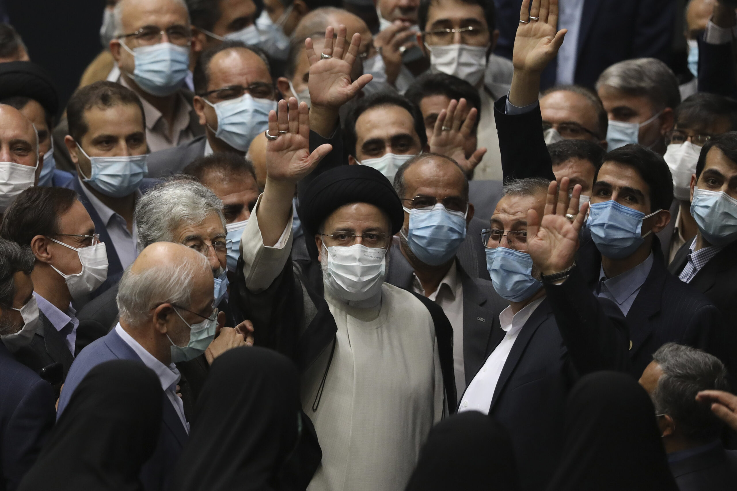 Iranian President Ebrahim Raisi, center, waves to journalists as he is surrounded by lawmakers after taking his oath as president at the Parliament in Tehran, Iran, Aug. 5. (AP Photo/Vahid Salemi)