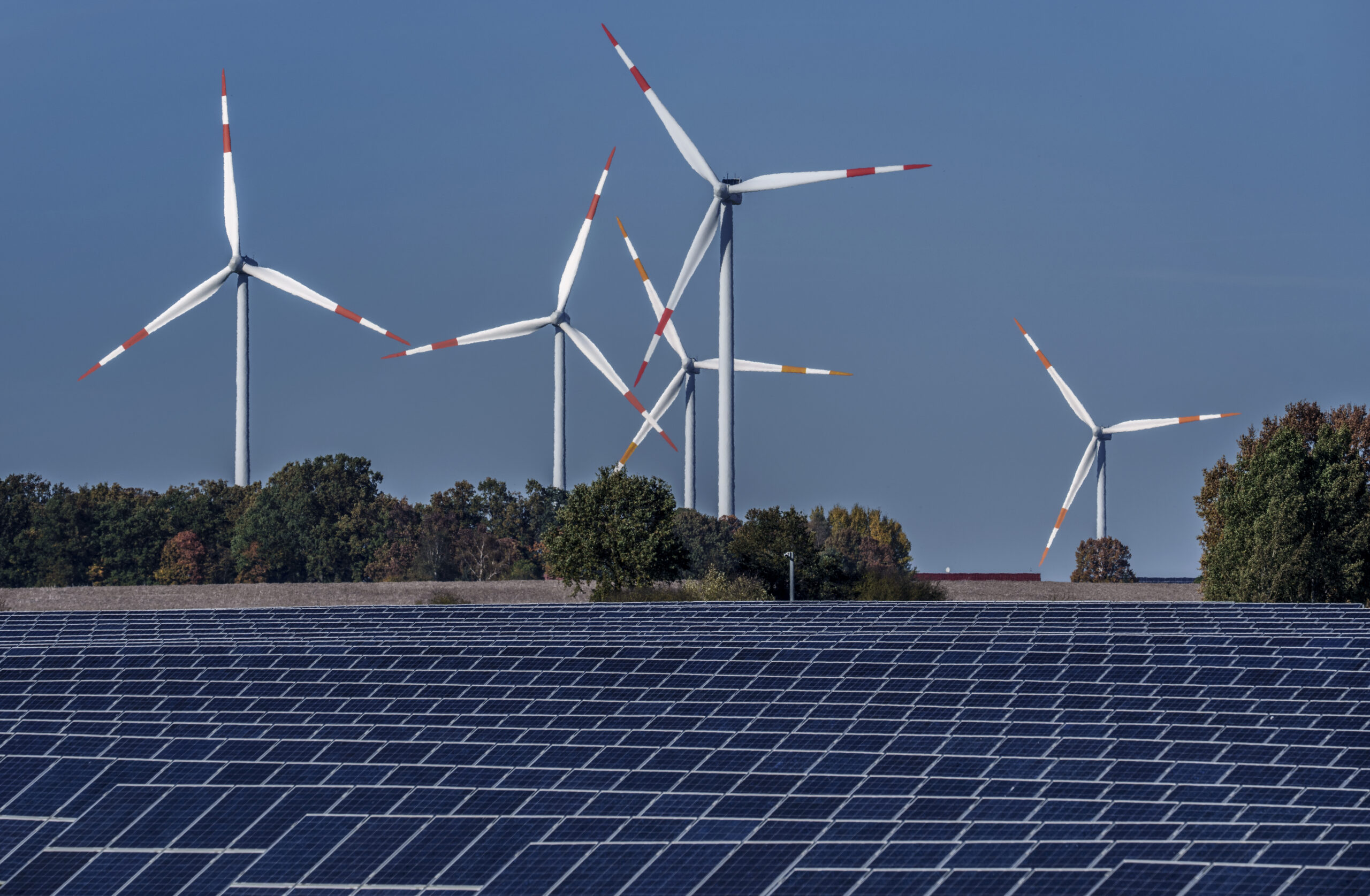 Wind turbines turn behind a solar farm in Rapshagen, Germany, Oct. 28. (AP Photo/Michael Sohn)