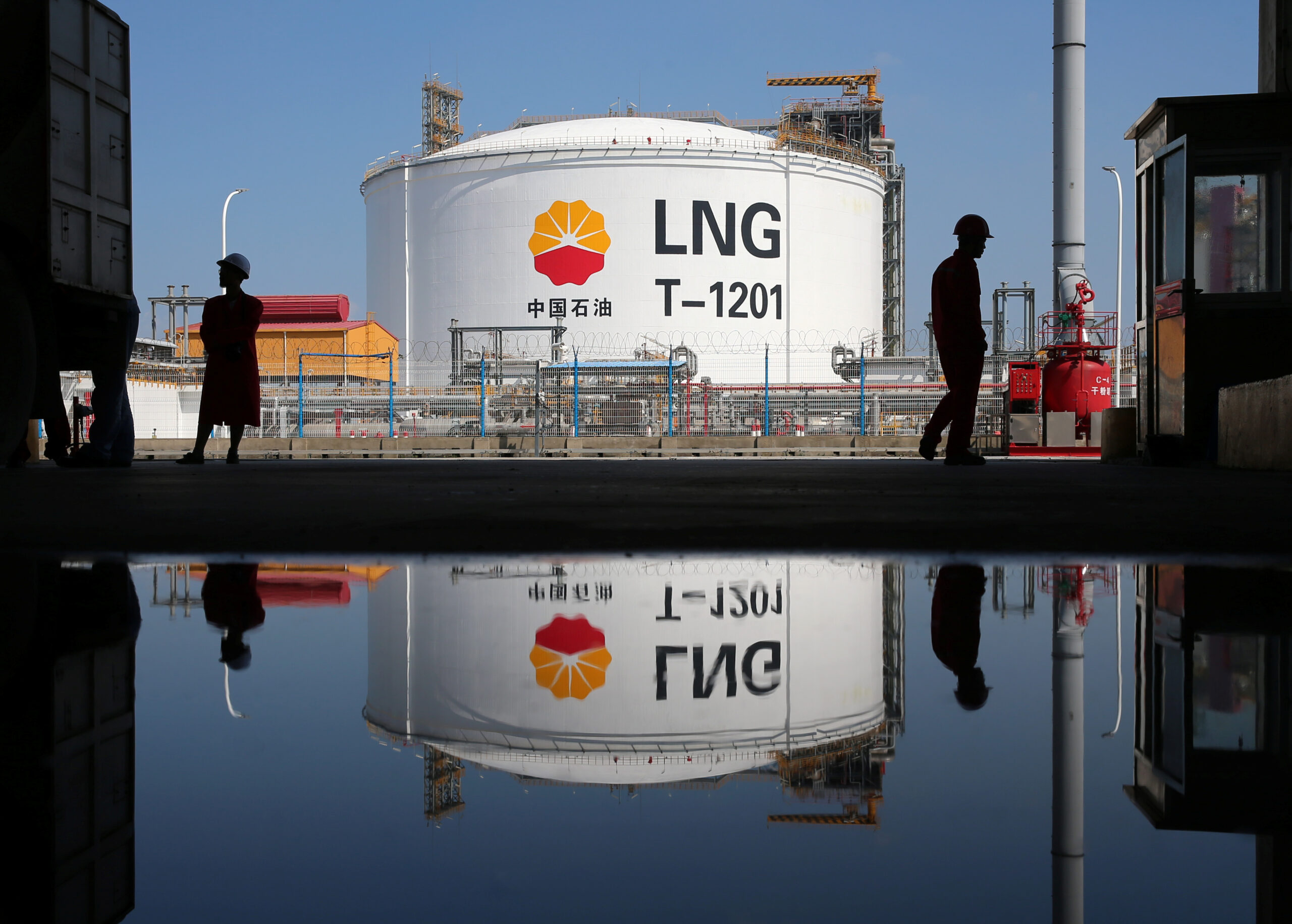 A liquefied natural gas storage tank and workers are reflected in a puddle at PetroChina's receiving terminal at Rudong port in Nantong, Jiangsu province, China September 4, 2018. (REUTERS/Stringer)