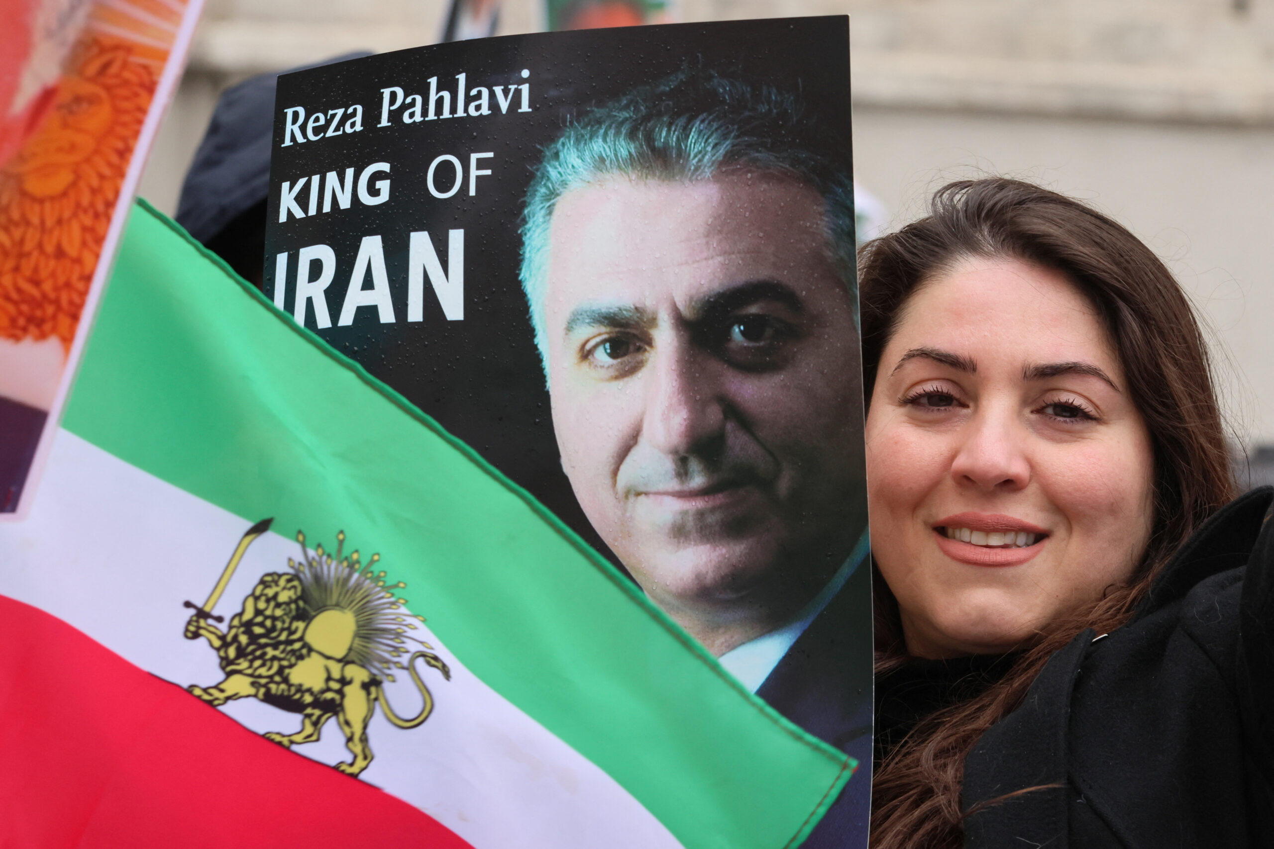 A woman poses next to an Iranian flag and photo of Reza Pahlavi during a protest in Munich, Germany February 17. (REUTERS/Wolfgang Rattay)