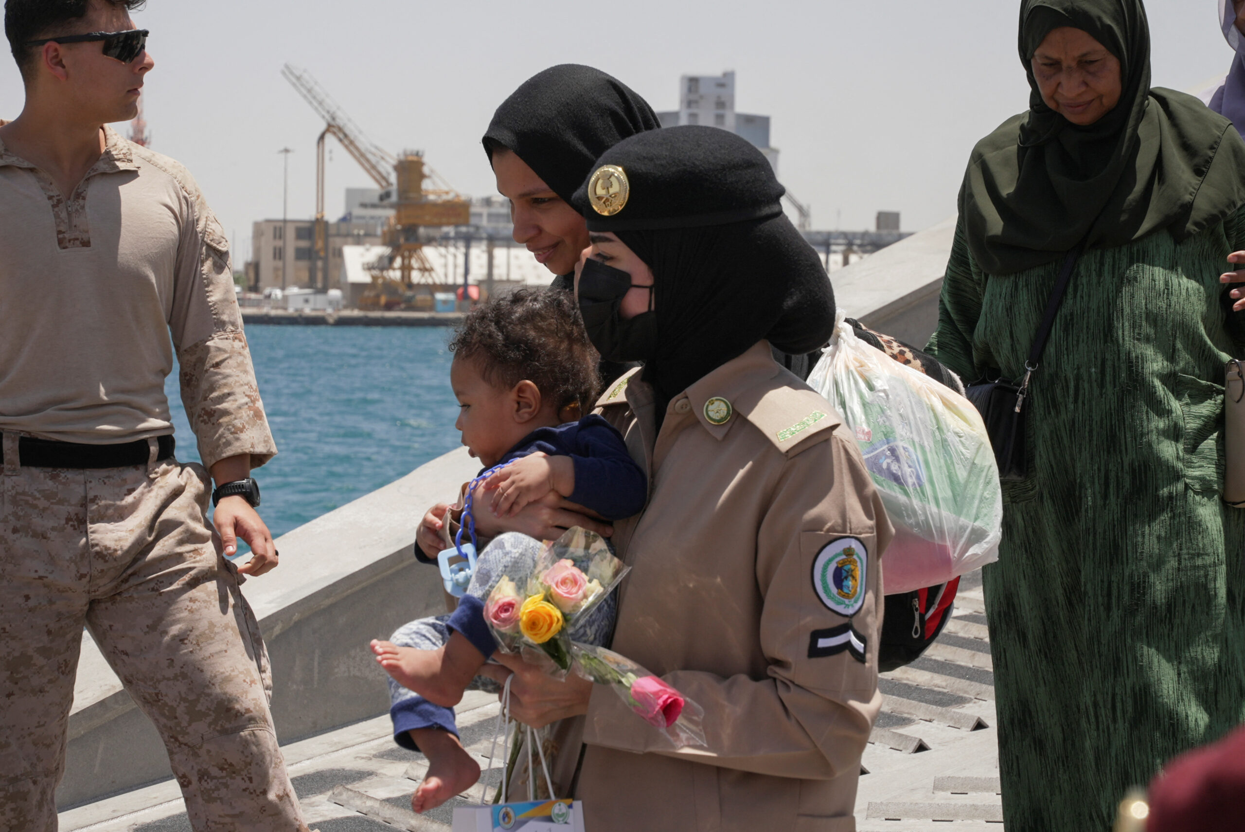 A Saudi Royal Navy female officer helps a woman disembark from a U.S. Navy fast transport ship at the Jeddah Sea Port, Jeddah, Saudi Arabia, May 1. (REUTERS/Mohammed Benmansour)