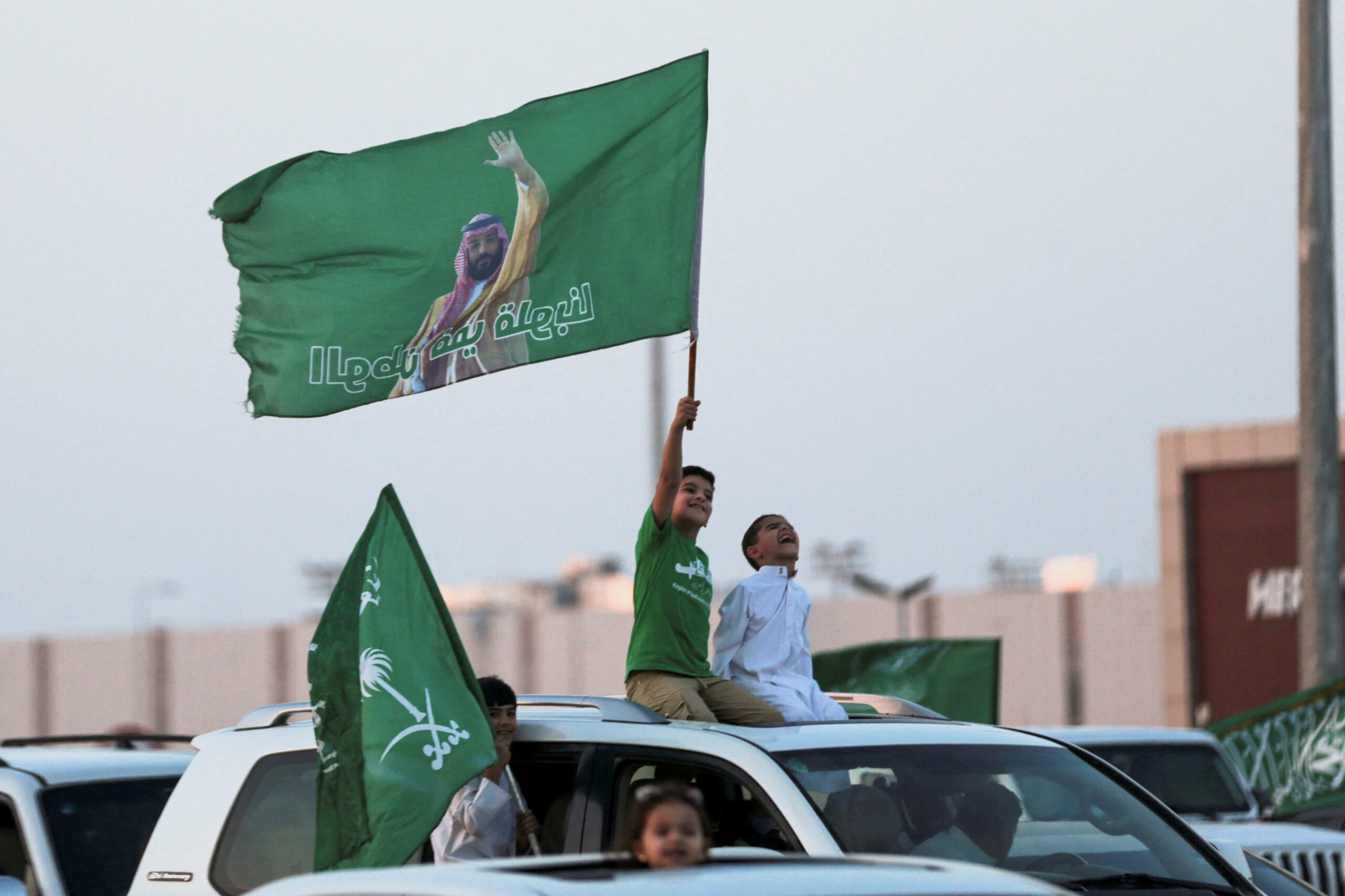Saudi youth hold a Saudi Nnational flag while celebrating Saudi Arabia's National Day in Riyadh, Saudi Arabia, September 23, 2023.