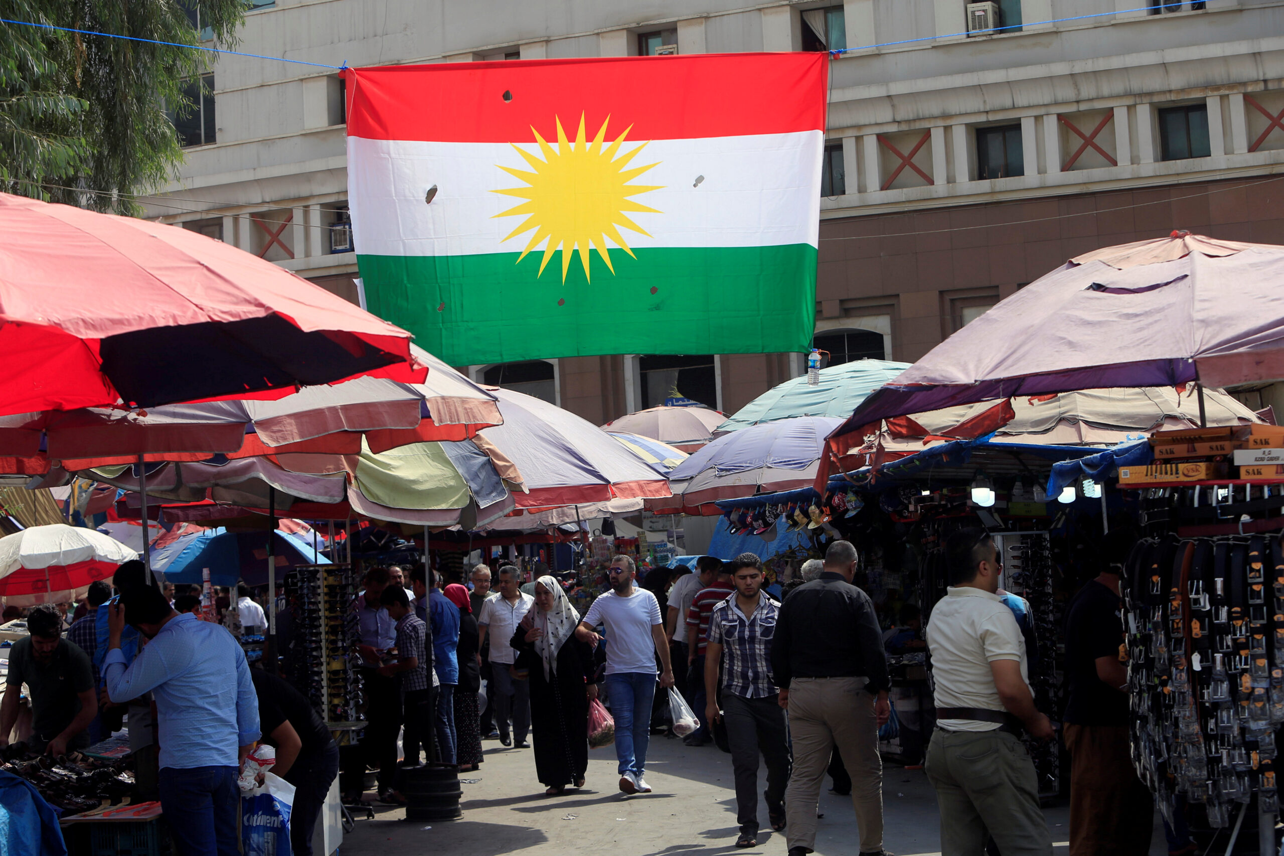 People walk at a market, near a Kurdish flag in Erbil, Iraq September 21, 2017. (REUTERS/Alaa Al-Marjani)