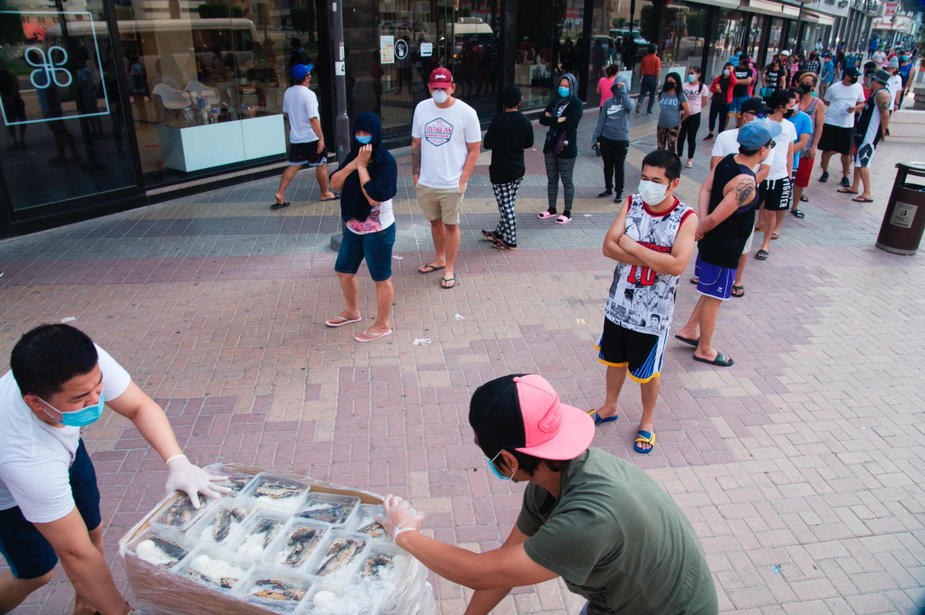 Esperidion Jr. Artillaga Dela Pena and Gary Dela Pena, both of Laguna, Philippines, wheel out free food for a line of people in Dubai, United Arab Emirates, June 3. (AP Photo/Jon Gambrell)