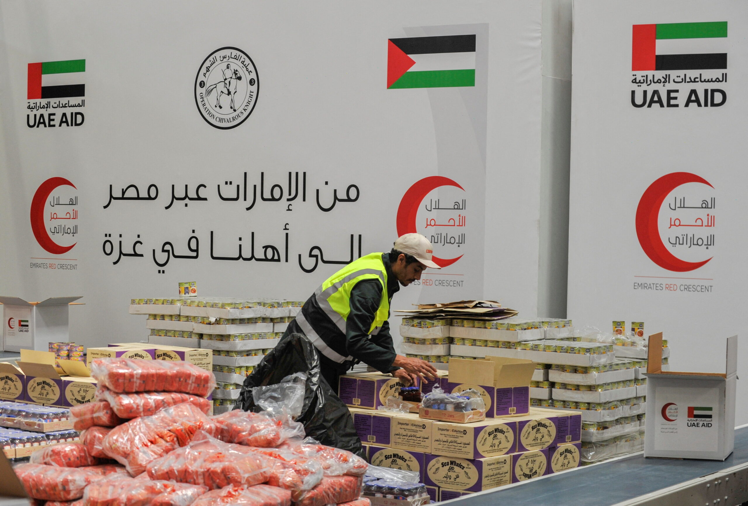 A volunteer from Emirates Red Crescent prepares parcels with humanitarian aid for Gaza to be transferred through the Rafah border crossing between Egypt and the Gaza Strip, in Cairo, Egypt, March 30, 2024. (REUTERS/Shokry Hussien)
