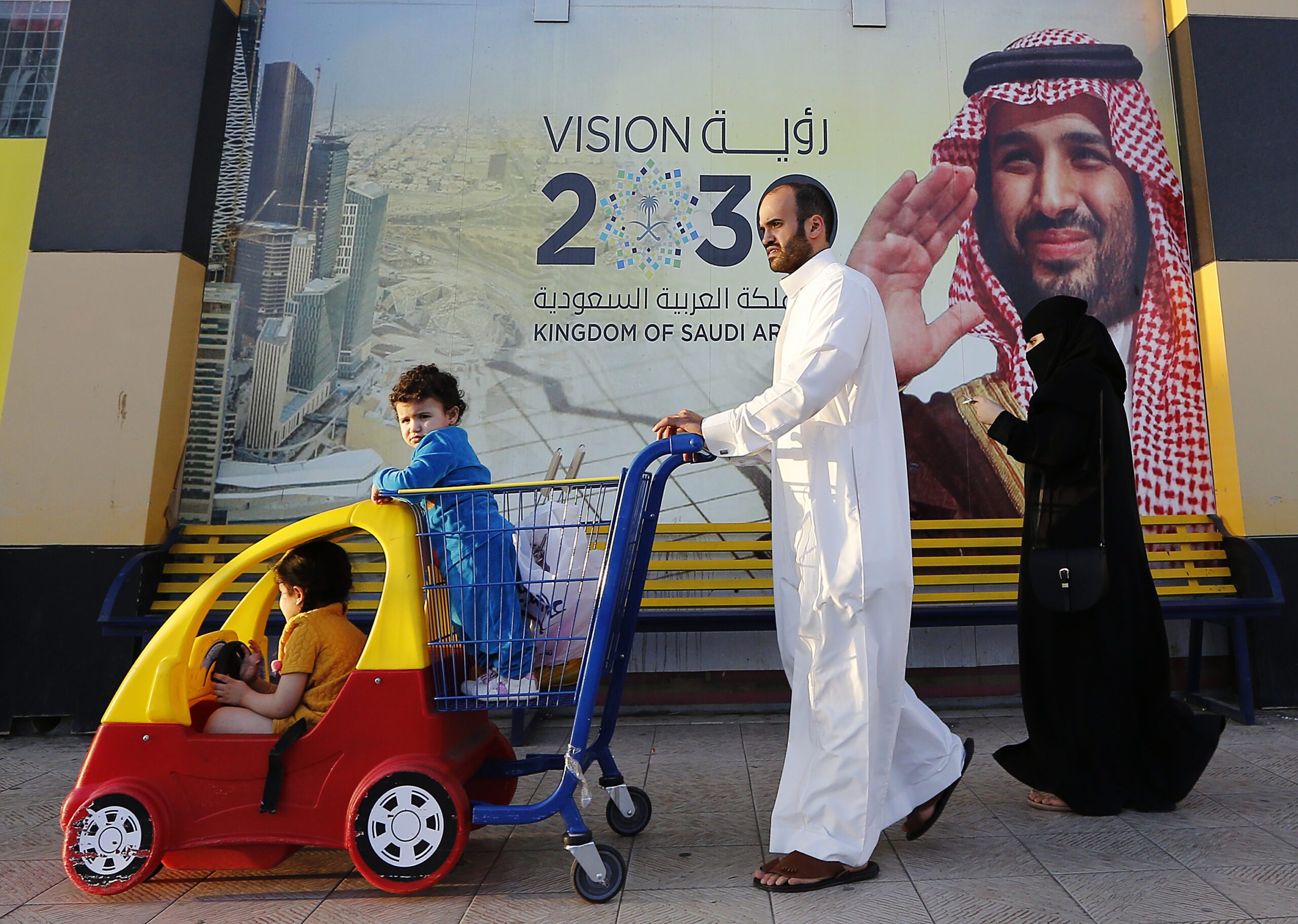 People walk past a banner showing Saudi Crown Prince Mohammed bin Salman outside a mall in Jeddah, Saudi Arabia, Feb. 5, 2020. (AP Photo/Amr Nabil)