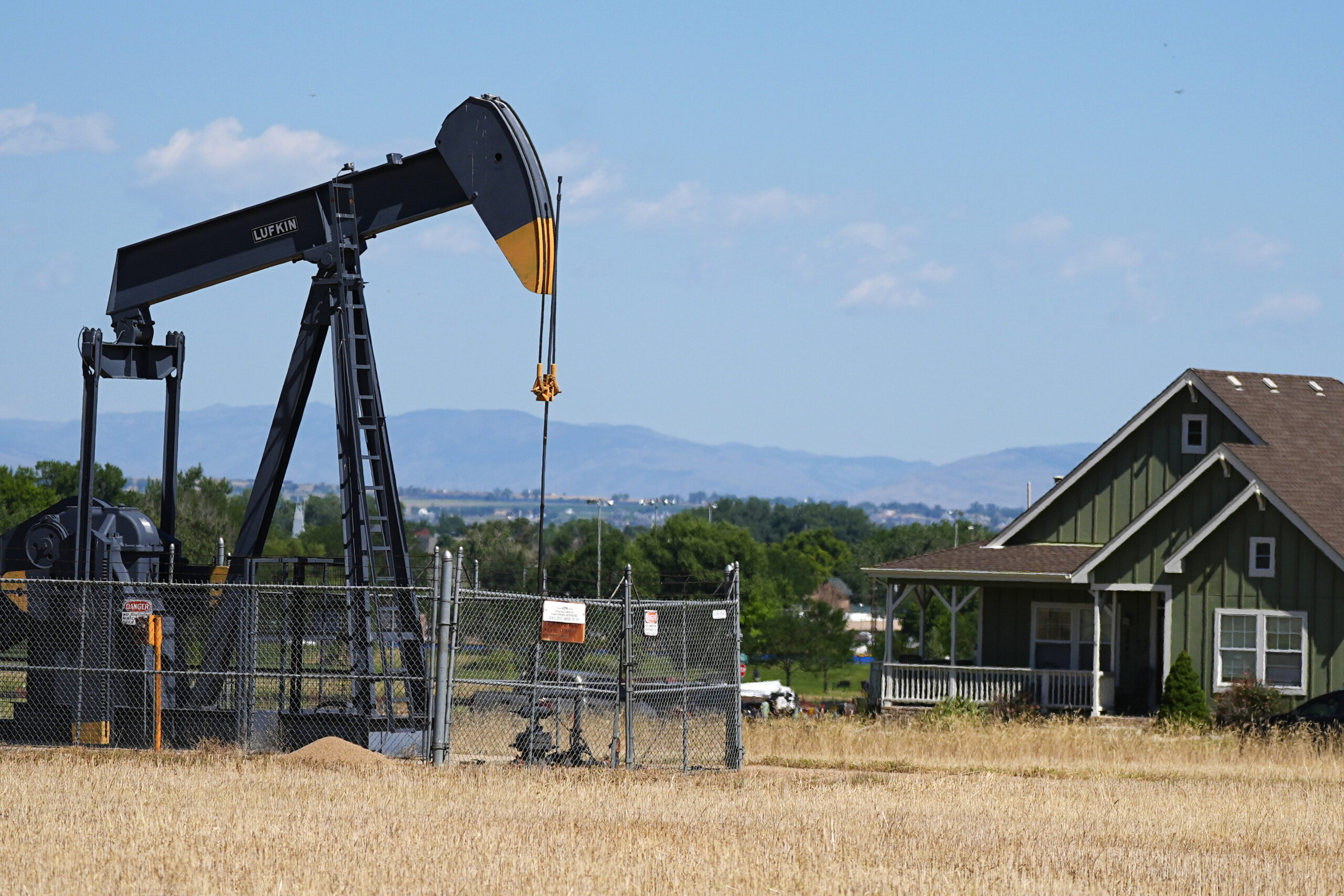A pumpjack works on a pad near a housing development in Dacono, Colorado, July 4, 2024. (AP Photo/David Zalubowski, File)