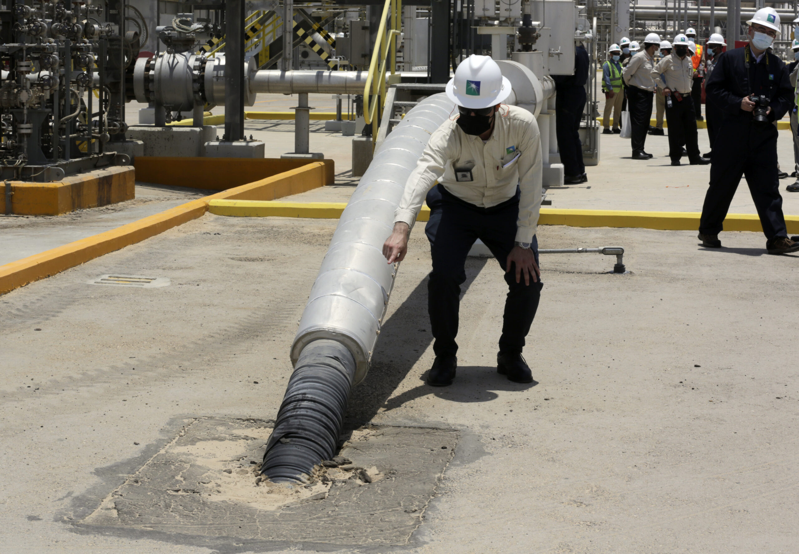 A Saudi Aramco engineer points at a tube that contains CO2 at the Hawiyah Natural Gas Liquids Recovery Plant in Hawiyah, Saudi Arabia, June 28, 2021. (AP Photo/Amr Nabil)