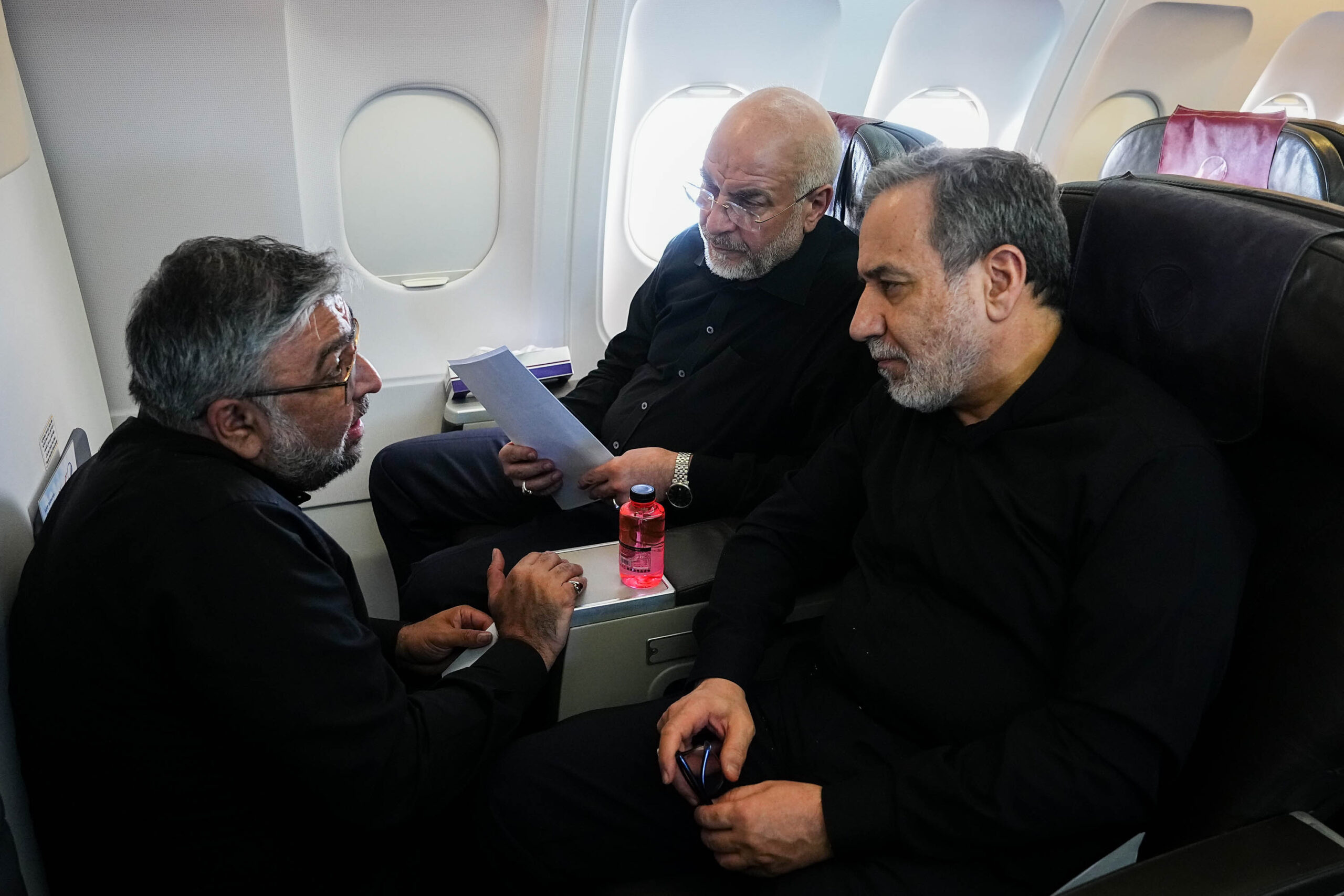 Iran's parliamentary speaker and top negotiator, Mohammad-Bagher Qalibaf, and foreign minister, Abbas Araghchi, listen to Abolfazl Amouei, Qalibaf's international affairs assistant, during a flight to Switzerland, June 21. (Hamed Malekpour/ICANA via AP)