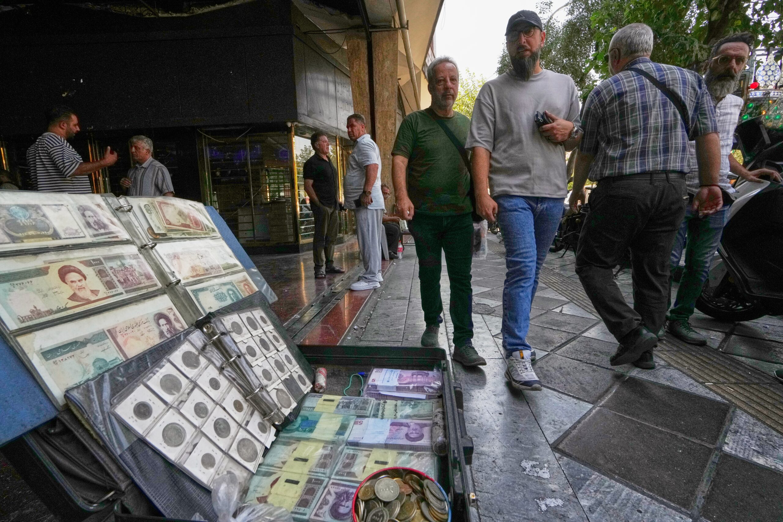 Pedestrians walk past a sidewalk display of Iranian currency and vintage banknotes and coins near Ferdowsi Square, a hub for currency trading in downtown Tehran, Iran, August 24. (AP Photo/Vahid Salemi)